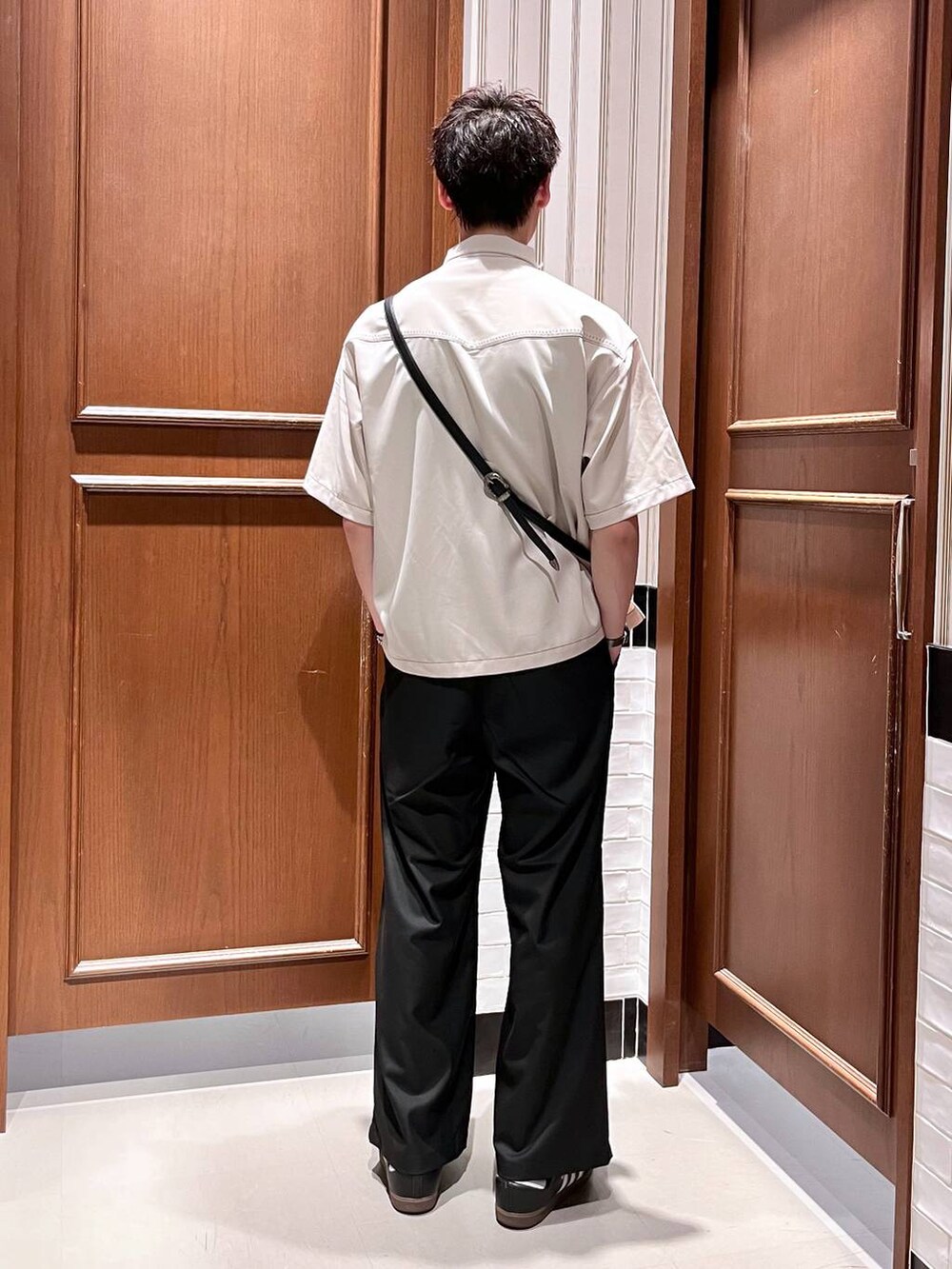 ブラック系のスラックス、ブラック系のショルダーバッグ、ホワイト系のシャツ/ブラウスを着用したメンズの夏コーディネートの4枚目の写真