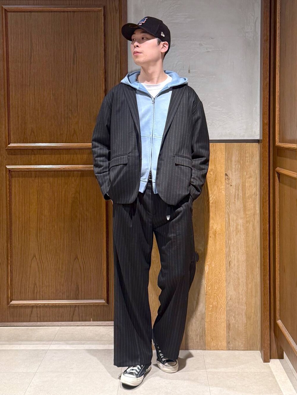 ブラック系のスラックス、ブラック系のテーラードジャケット、ブルー系のパーカーを着用したメンズの冬コーディネートの3枚目の写真