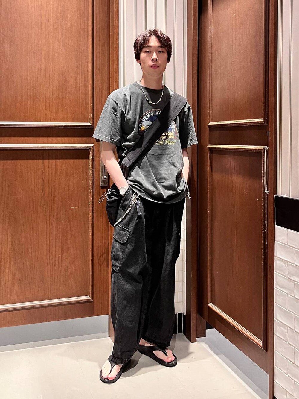 ブラック系のサンダル、グレー系のデニムパンツ、ブラック系のショルダーバッグを着用したメンズの夏コーディネートの5枚目の写真