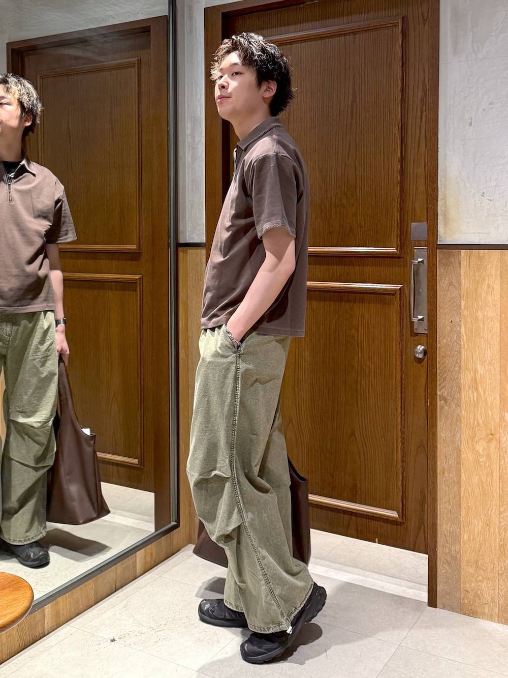 ブラウン系のトートバッグ、グリーン系のカーゴパンツ、ブラウン系のTシャツ/カットソーを着用したメンズの春コーディネートの3枚目の写真