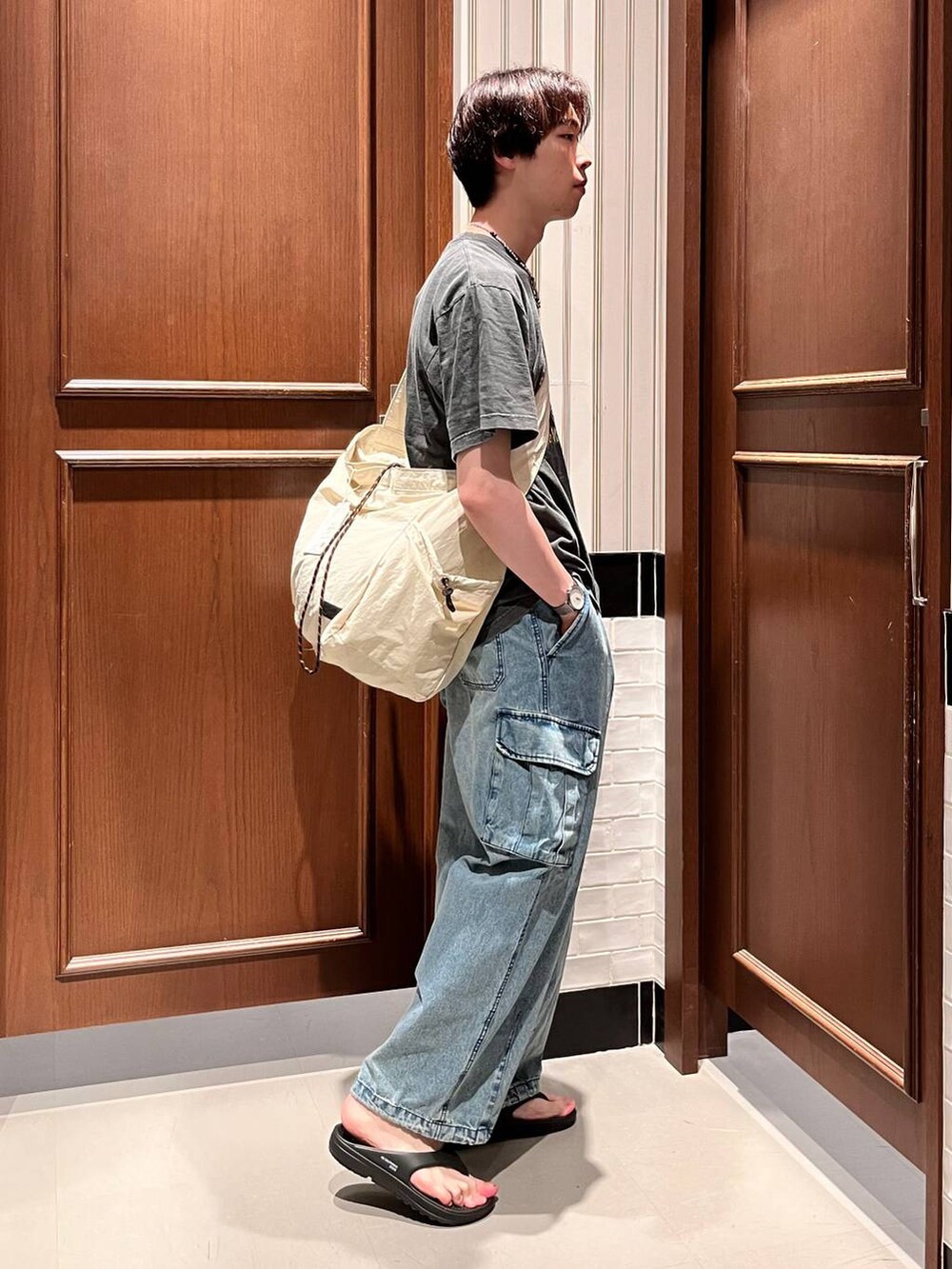 ブラック系のサンダル、ブルー系のデニムパンツ、ホワイト系のショルダーバッグを着用したメンズの夏コーディネートの6枚目の写真