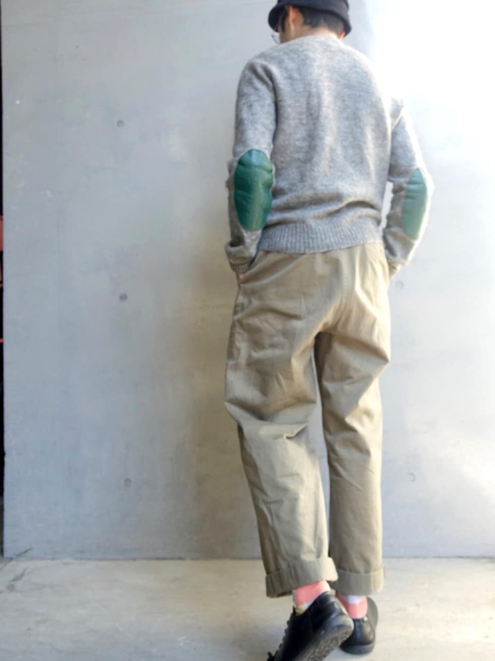 グレー系のニット/セーター、グリーン系のチノパンツ、ブラック系のスニーカーを着用したメンズの冬コーディネートの2枚目の写真