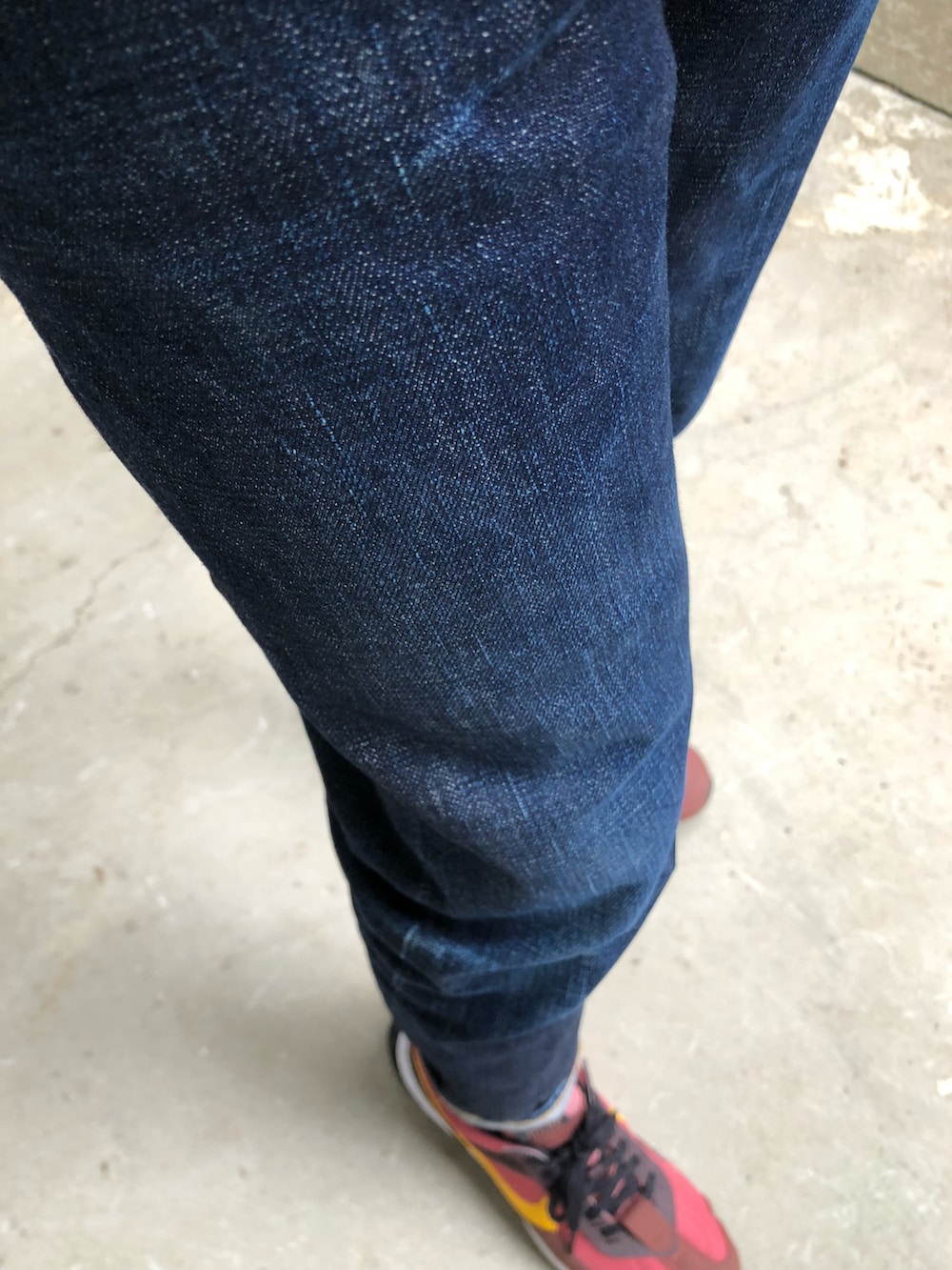 ブラック系のブルゾン、ブルー系のデニムパンツ、レッド系のスニーカーを着用したメンズの秋コーディネートの3枚目の写真