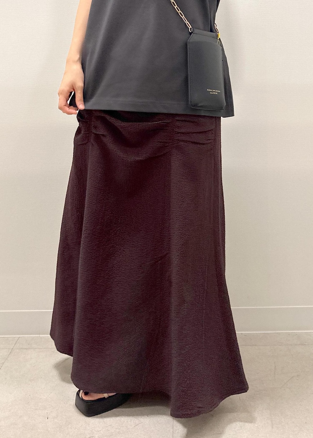 ブラック系のショルダーバッグ、ゴールド系のサンダル、グレー系のTシャツ/カットソーを着用したレディースの夏コーディネートの10枚目の写真