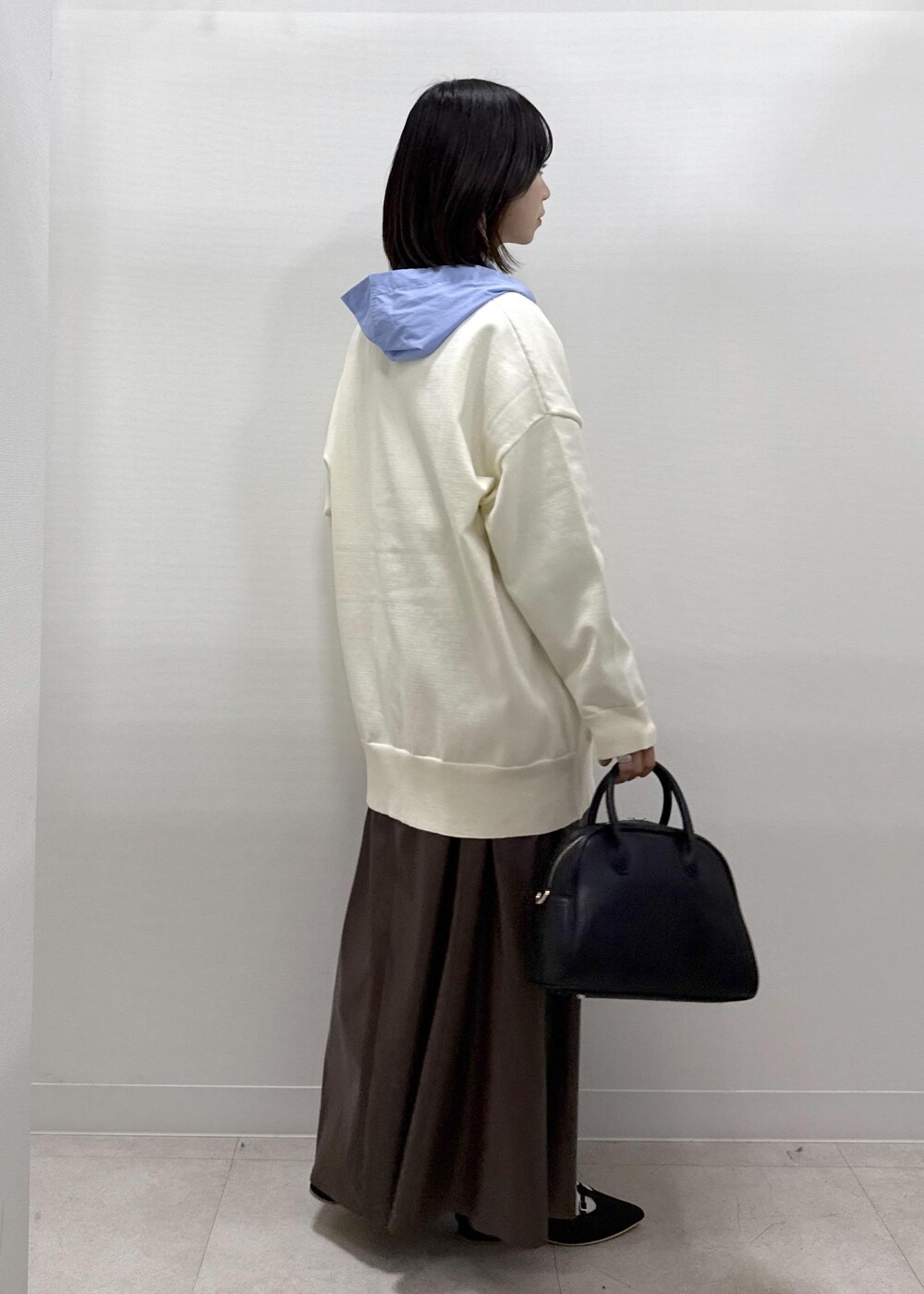 ブラウン系のスカート、ブラック系のパンプス、ブルー系のシャツ/ブラウスを着用したレディースの秋コーディネートの6枚目の写真