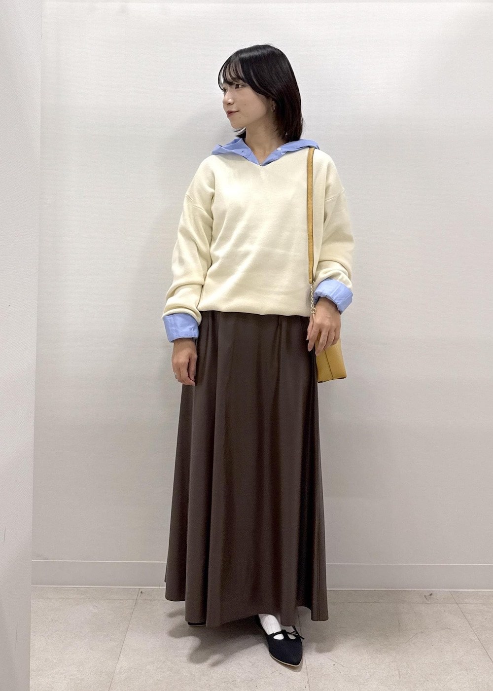 ブラウン系のショルダーバッグ、ブラウン系のスカート、ブラック系のパンプスを着用したレディースの秋コーディネートの9枚目の写真