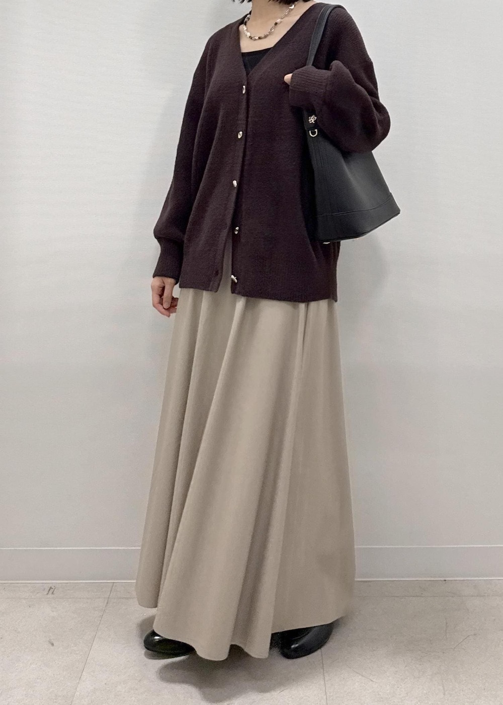 ベージュ系のスカート、ブラウン系のカーディガン/ボレロ、ブラック系のローファーを着用したレディースの秋コーディネートの2枚目の写真