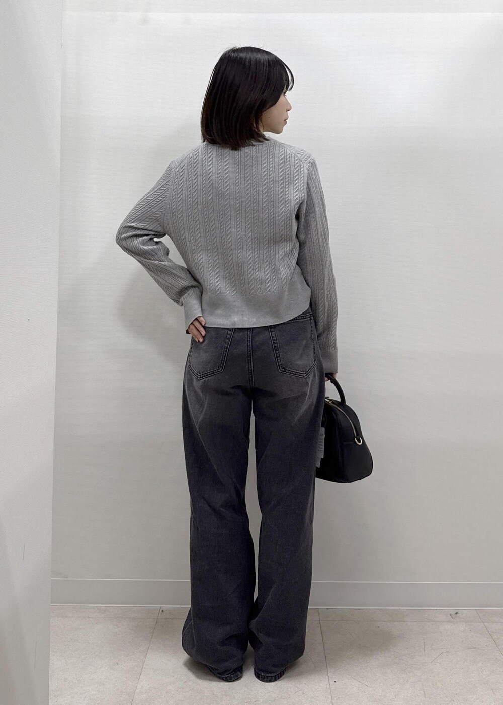 ブラック系のデニムパンツ、グレー系のカーディガン/ボレロ、ブラック系のショルダーバッグを着用したレディースの秋コーディネートの5枚目の写真