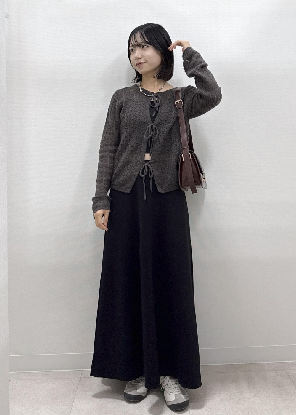 ブラック系のスカート、ブラウン系のカーディガン/ボレロ、レッド系のショルダーバッグを着用したレディースの秋コーディネートの3枚目の写真