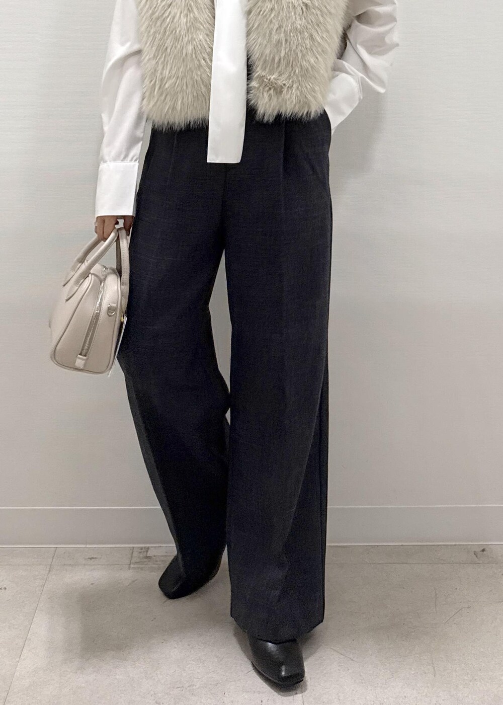 ベージュ系のベスト、ホワイト系のシャツ/ブラウス、グレー系のスラックスを着用したレディースの秋コーディネートの2枚目の写真