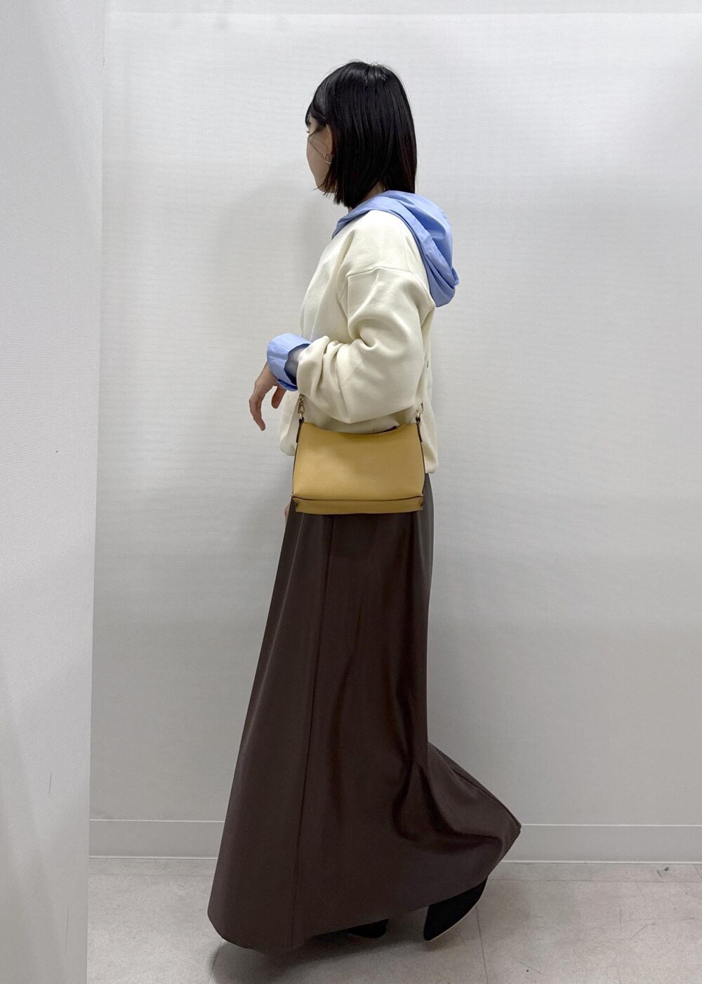 ブラウン系のショルダーバッグ、ブラウン系のスカート、ブラック系のパンプスを着用したレディースの秋コーディネートの4枚目の写真