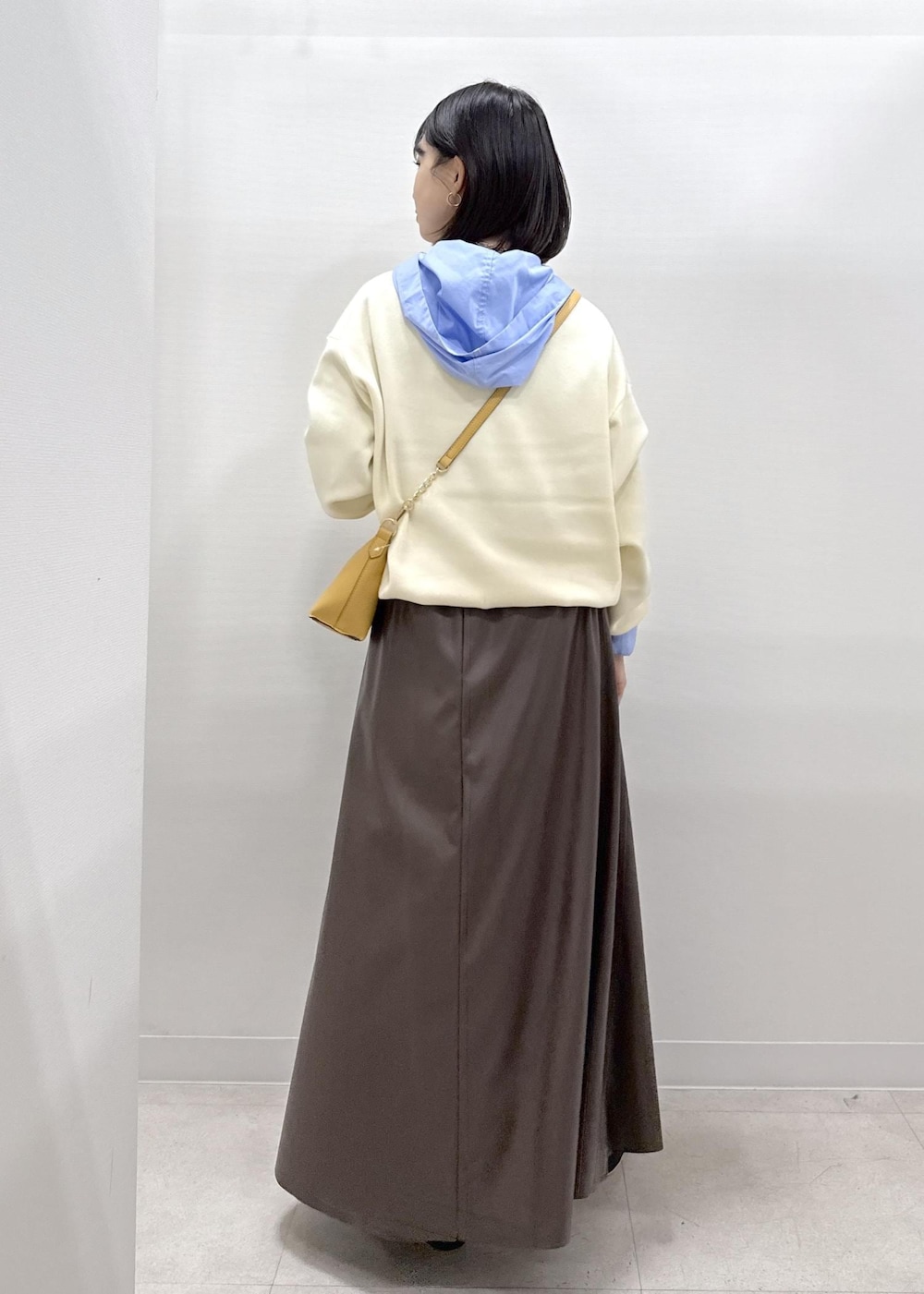 ブラウン系のショルダーバッグ、ブラウン系のスカート、ブラック系のパンプスを着用したレディースの秋コーディネートの5枚目の写真