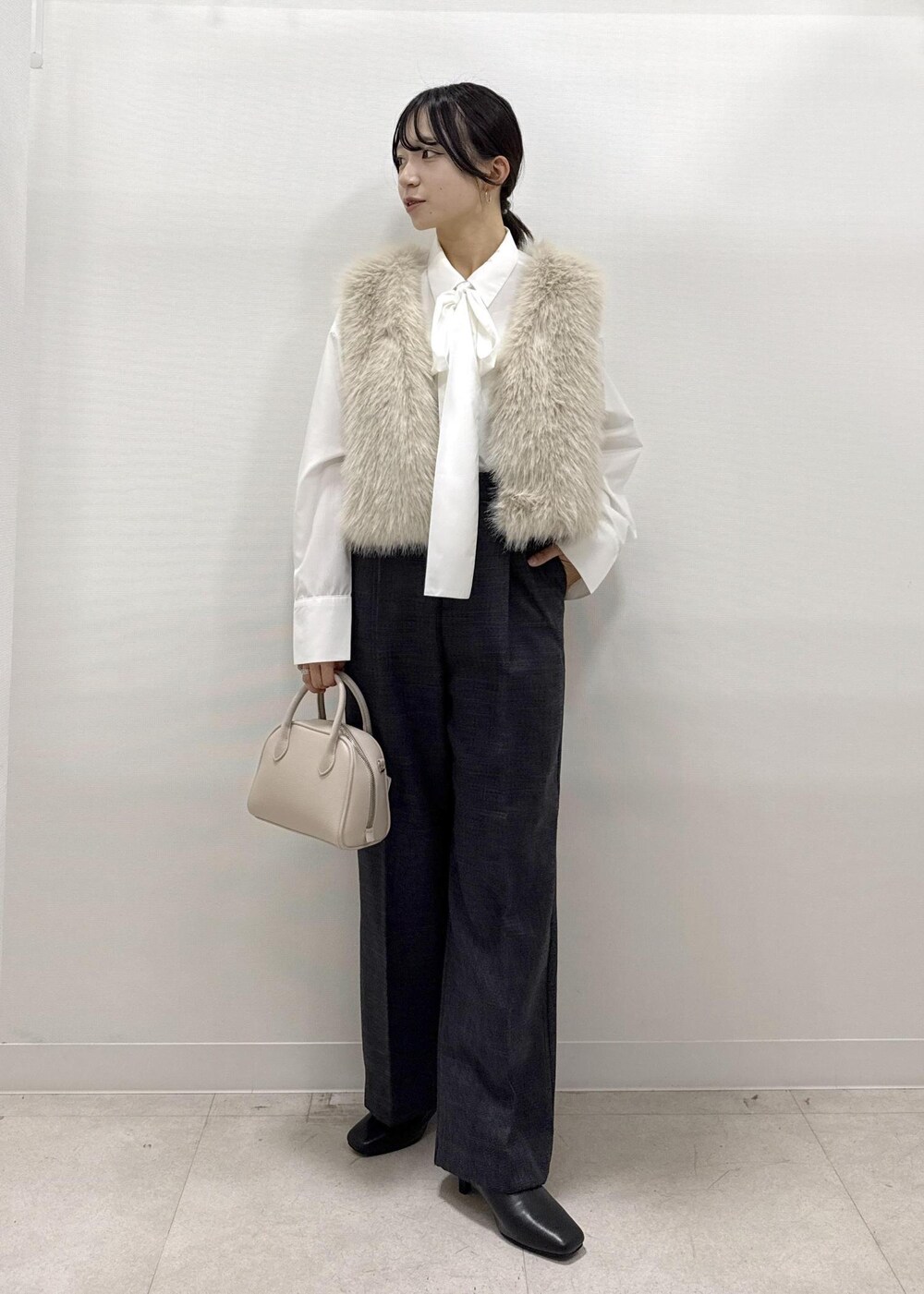 ベージュ系のベスト、ホワイト系のシャツ/ブラウス、グレー系のスラックスを着用したレディースの秋コーディネートの3枚目の写真