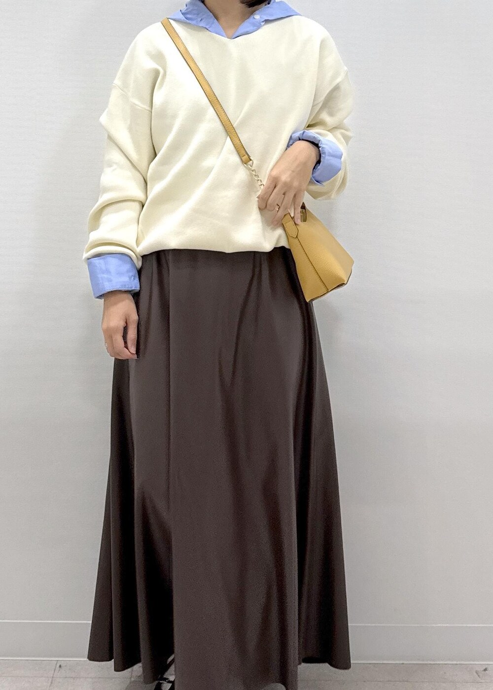 ブラウン系のショルダーバッグ、ブラウン系のスカート、ブラック系のパンプスを着用したレディースの秋コーディネートの3枚目の写真