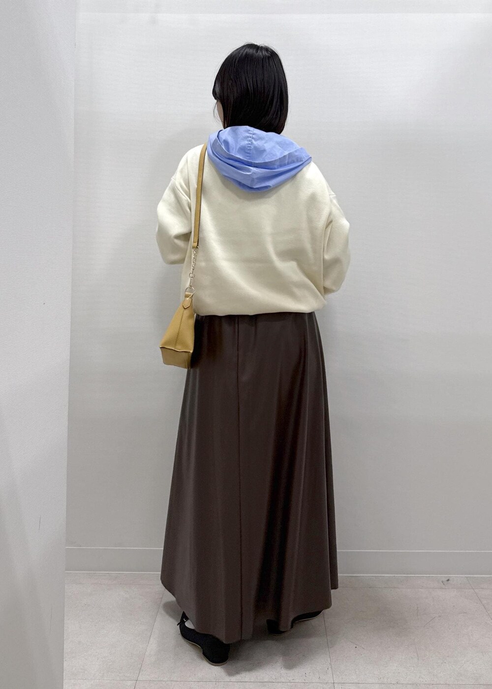 ブラウン系のショルダーバッグ、ブラウン系のスカート、ブラック系のパンプスを着用したレディースの秋コーディネートの7枚目の写真