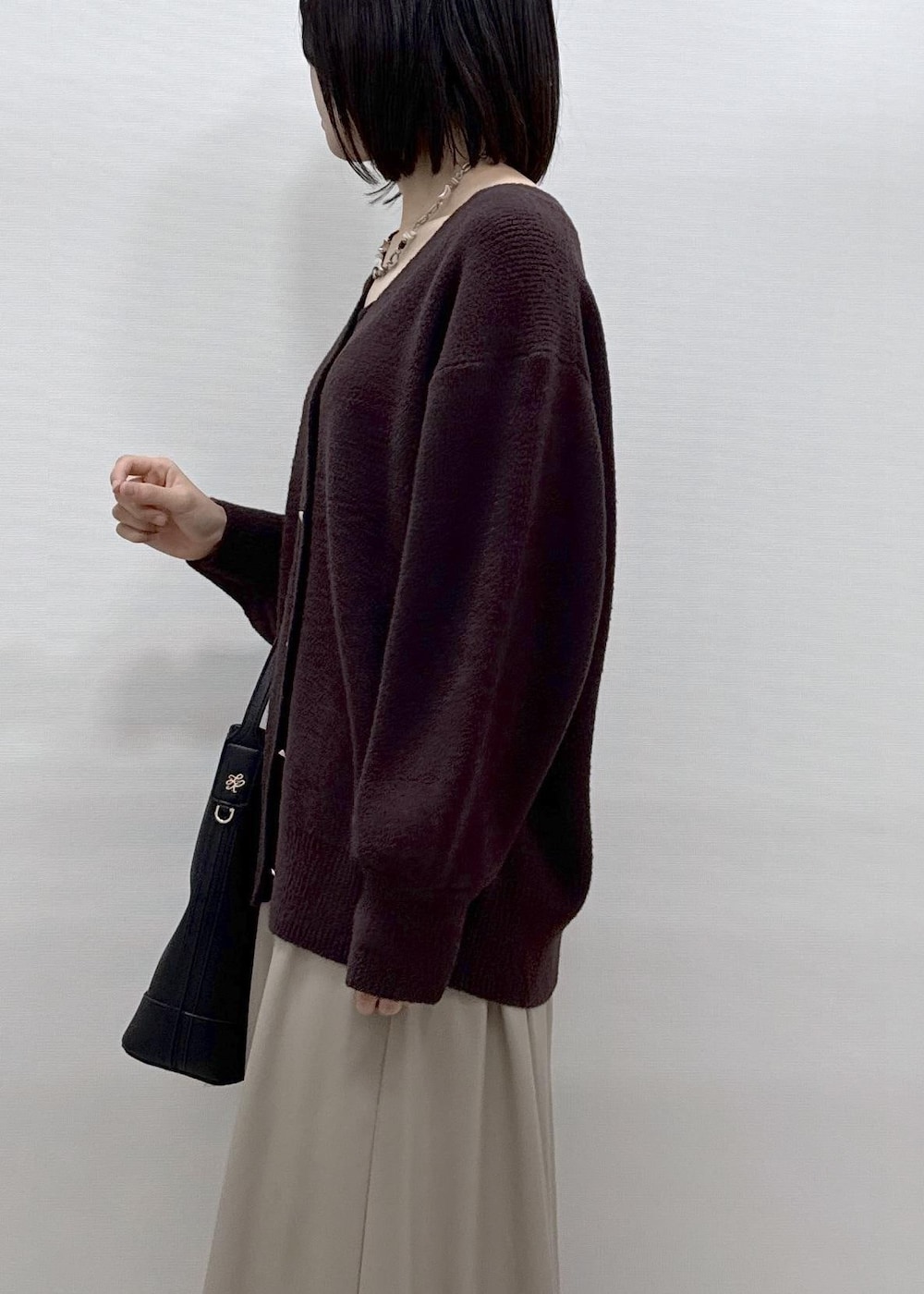 ベージュ系のスカート、ブラウン系のカーディガン/ボレロ、ブラック系のローファーを着用したレディースの秋コーディネートの4枚目の写真