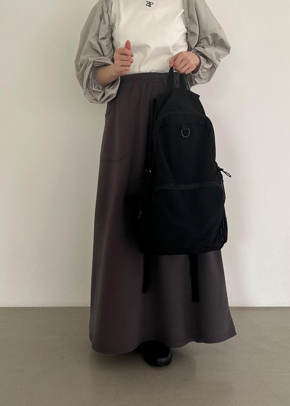 ブラック系のバックパック/リュック、グレー系のスカート、グレー系のその他アウターを着用したレディースの夏コーディネートの7枚目の写真