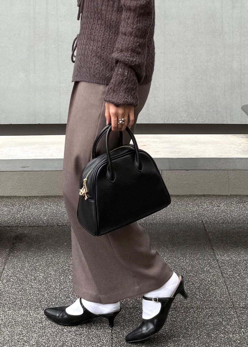 ブラウン系のカーディガン/ボレロ、ベージュ系のスラックス、ブラック系のボストンバッグを着用したレディースの秋コーディネートの4枚目の写真
