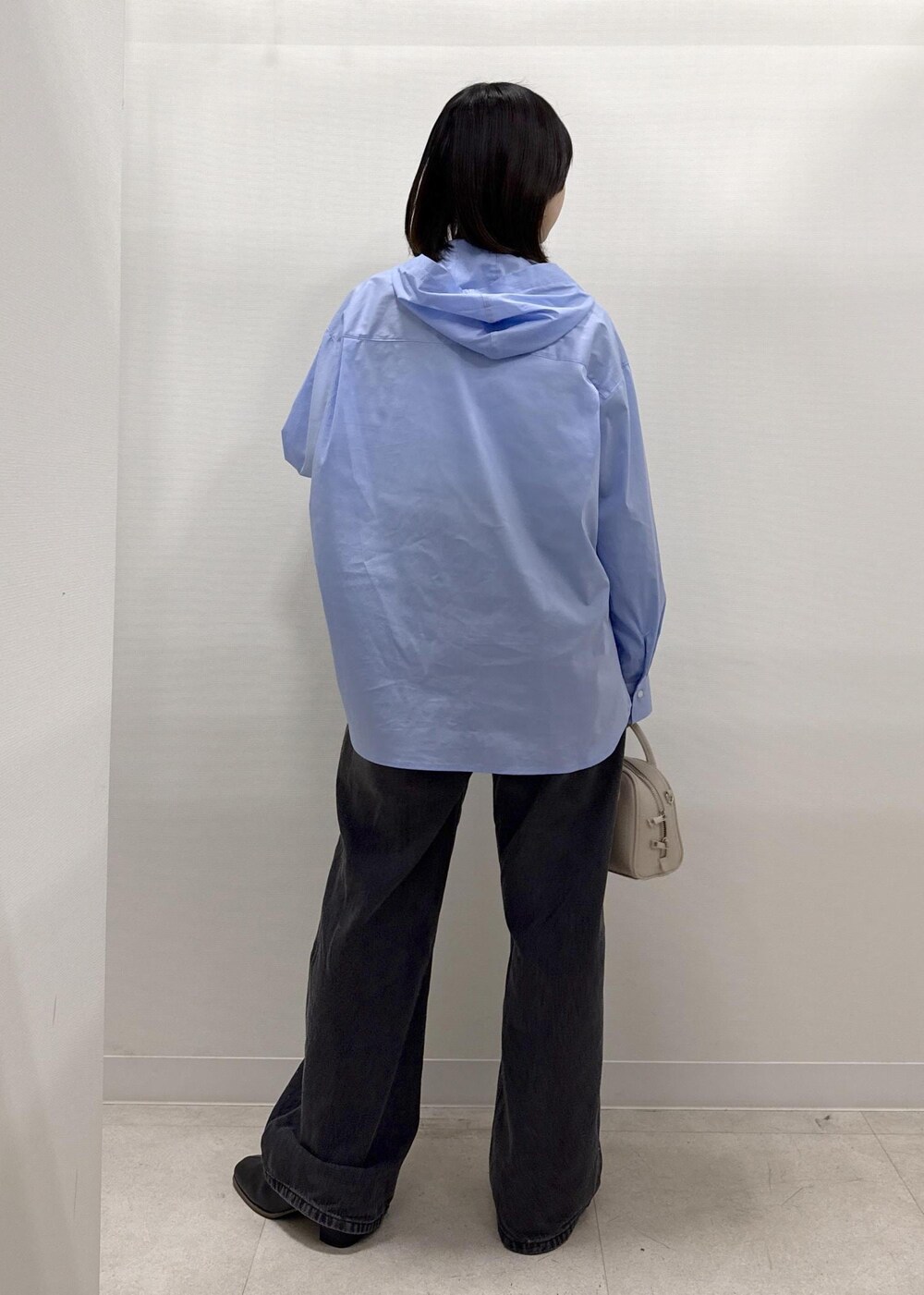 ブラック系のデニムパンツ、ブラック系のブーツ、ベージュ系のショルダーバッグを着用したレディースの秋コーディネートの4枚目の写真