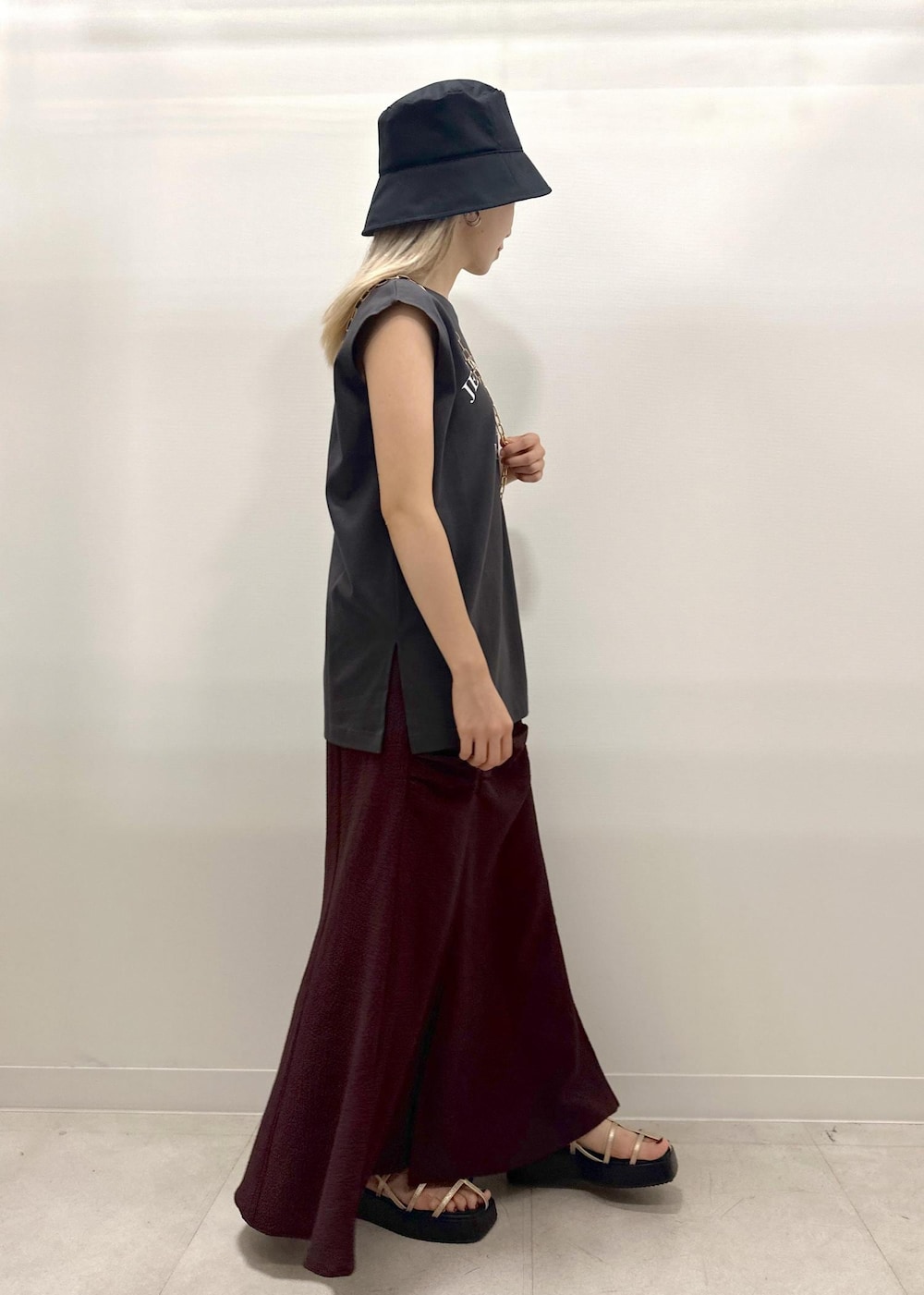 ブラック系のショルダーバッグ、ゴールド系のサンダル、グレー系のTシャツ/カットソーを着用したレディースの夏コーディネートの8枚目の写真