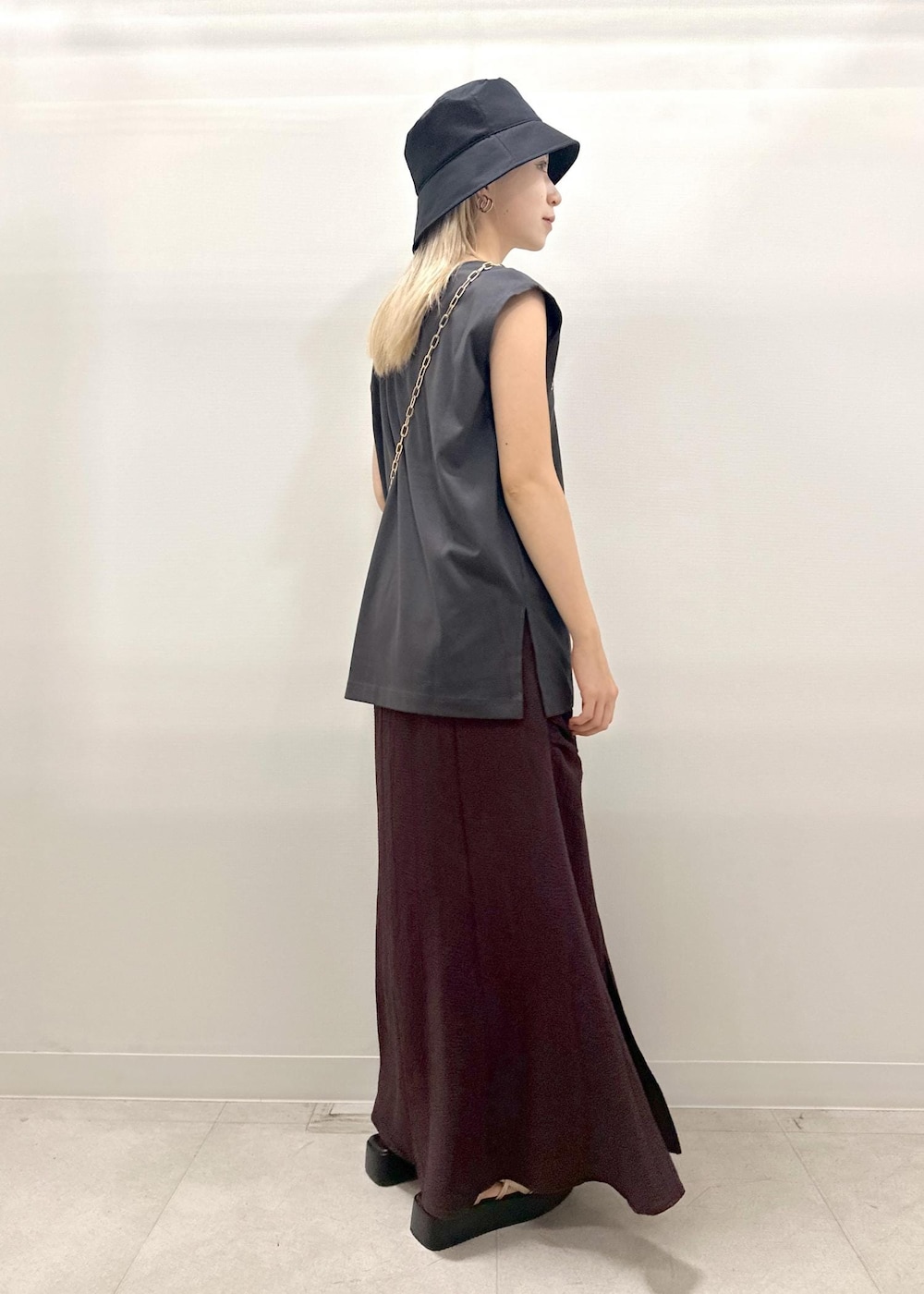 ブラック系のショルダーバッグ、ゴールド系のサンダル、グレー系のTシャツ/カットソーを着用したレディースの夏コーディネートの5枚目の写真