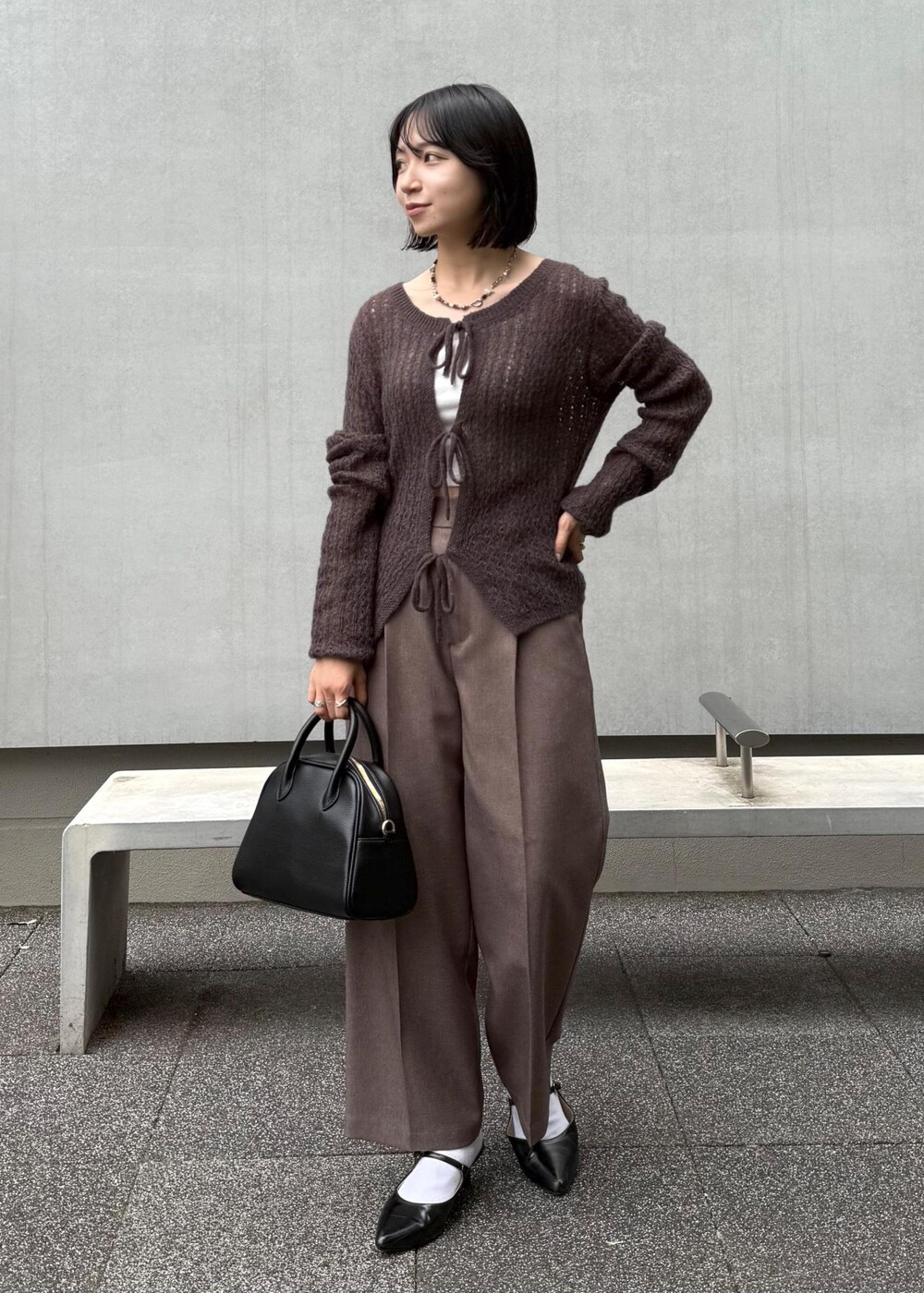 ブラウン系のカーディガン/ボレロ、ベージュ系のスラックス、ブラック系のボストンバッグを着用したレディースの秋コーディネートの2枚目の写真
