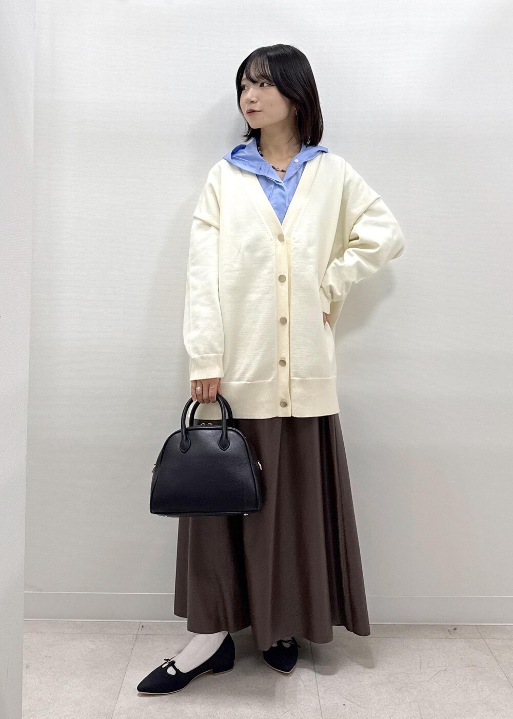 ブラウン系のスカート、ブラック系のパンプス、ブルー系のシャツ/ブラウスを着用したレディースの秋コーディネートの2枚目の写真