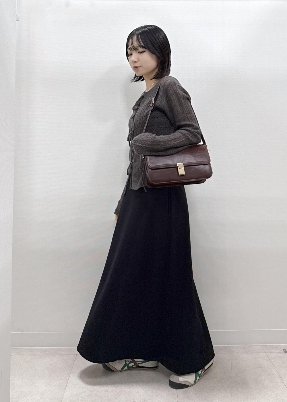 ブラック系のスカート、ブラウン系のカーディガン/ボレロ、レッド系のショルダーバッグを着用したレディースの秋コーディネートの2枚目の写真