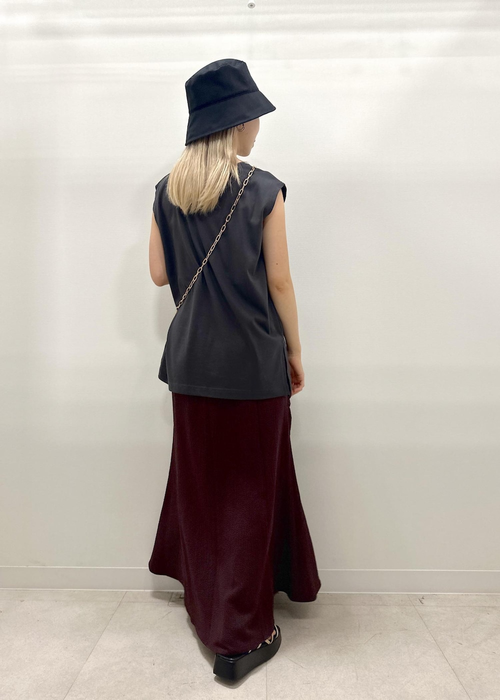 ブラック系のショルダーバッグ、ゴールド系のサンダル、グレー系のTシャツ/カットソーを着用したレディースの夏コーディネートの7枚目の写真