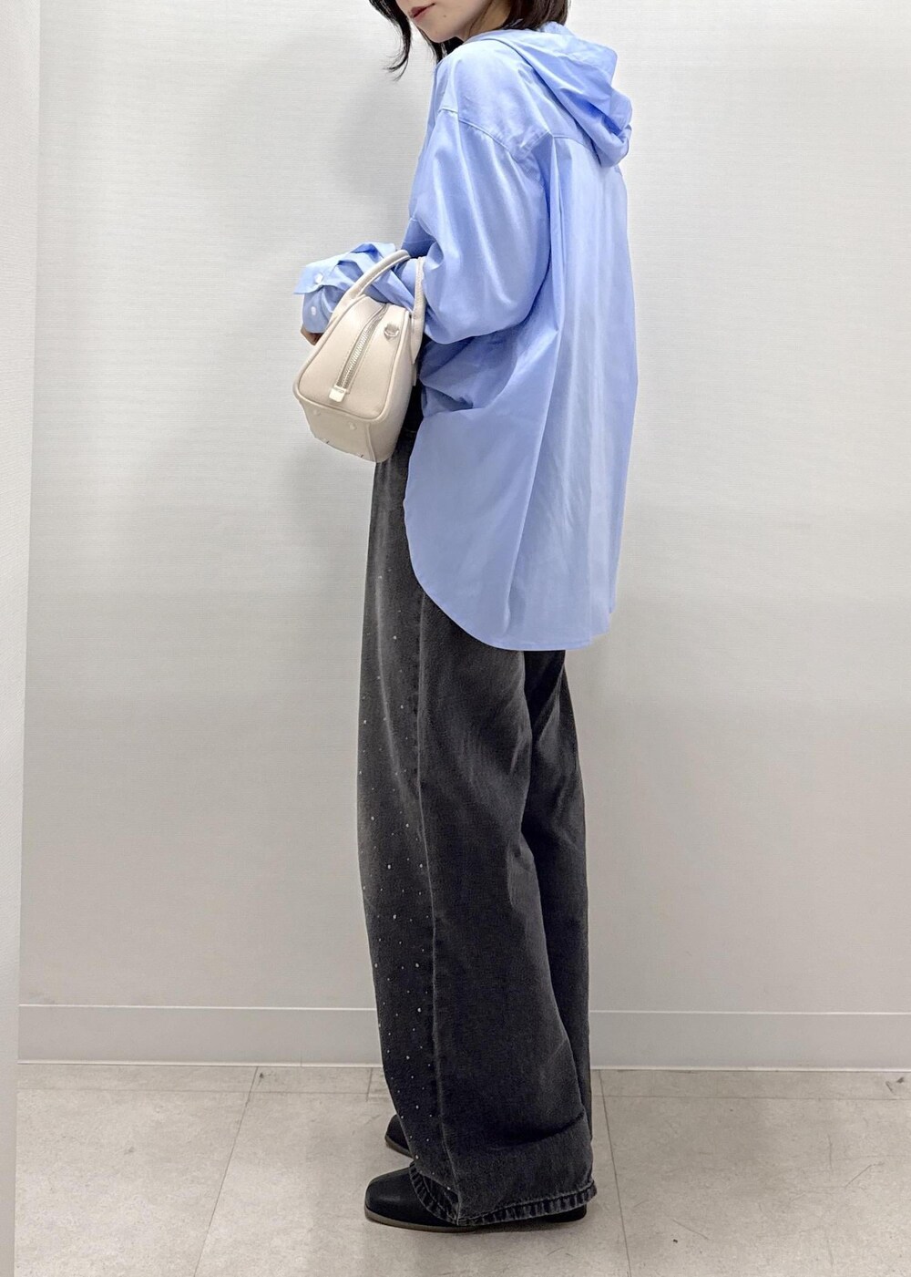 ブラック系のデニムパンツ、ブラック系のブーツ、ベージュ系のショルダーバッグを着用したレディースの秋コーディネートの8枚目の写真