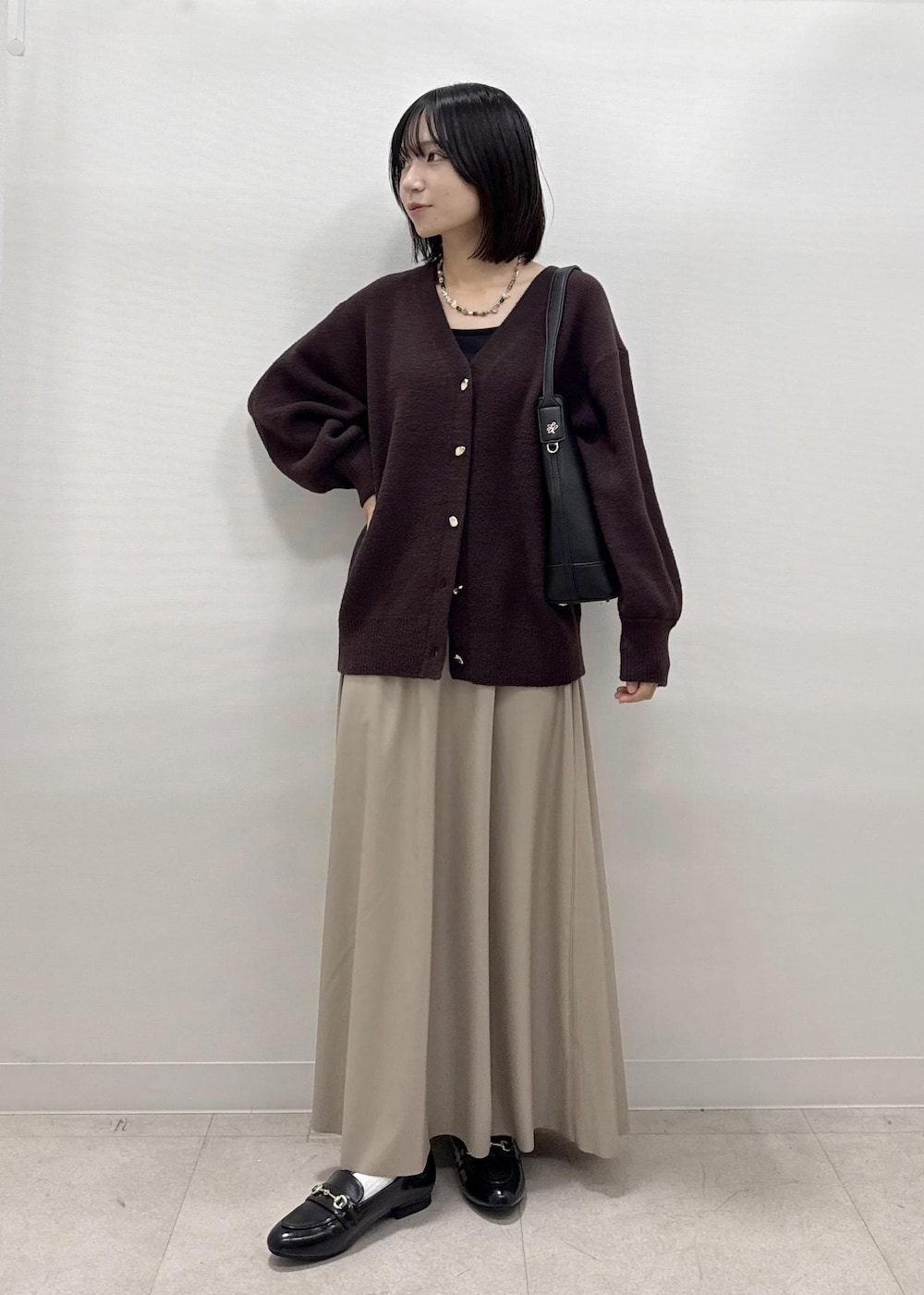 ベージュ系のスカート、ブラウン系のカーディガン/ボレロ、ブラック系のローファーを着用したレディースの秋コーディネートの8枚目の写真