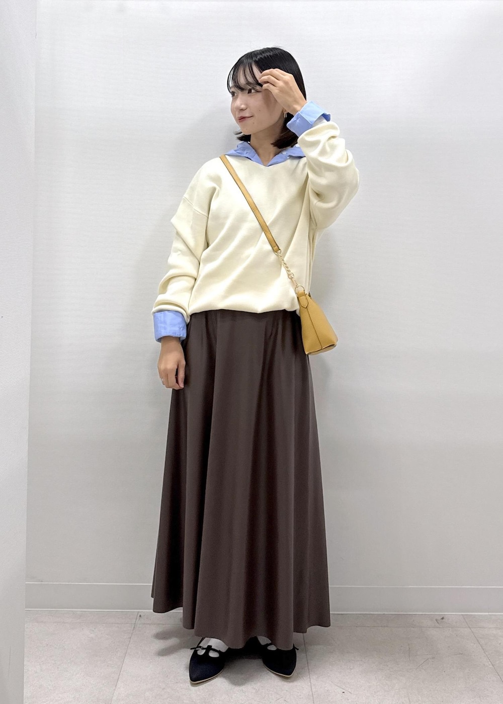 ブラウン系のショルダーバッグ、ブラウン系のスカート、ブラック系のパンプスを着用したレディースの秋コーディネートの2枚目の写真