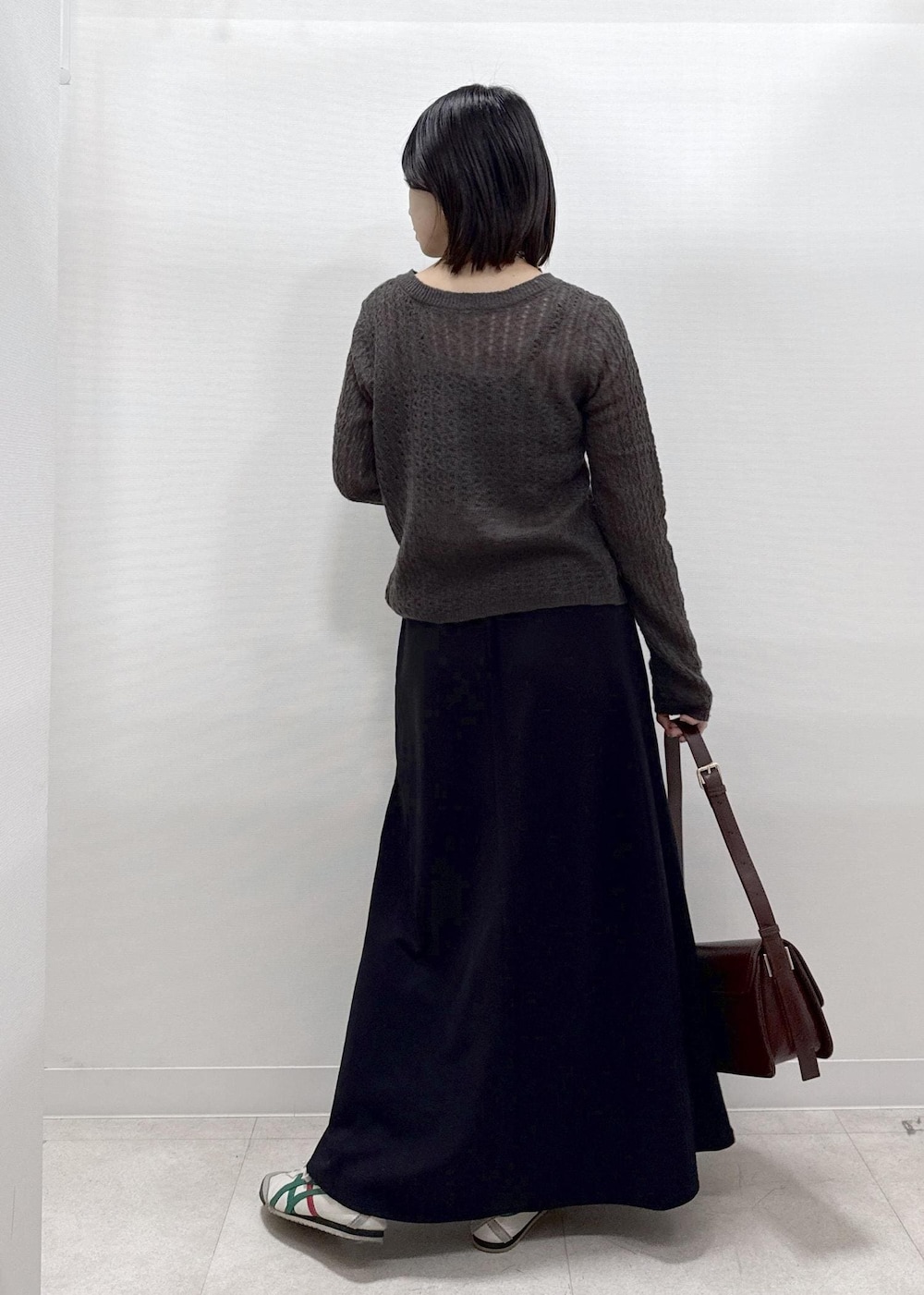 ブラック系のスカート、ブラウン系のカーディガン/ボレロ、レッド系のショルダーバッグを着用したレディースの秋コーディネートの6枚目の写真