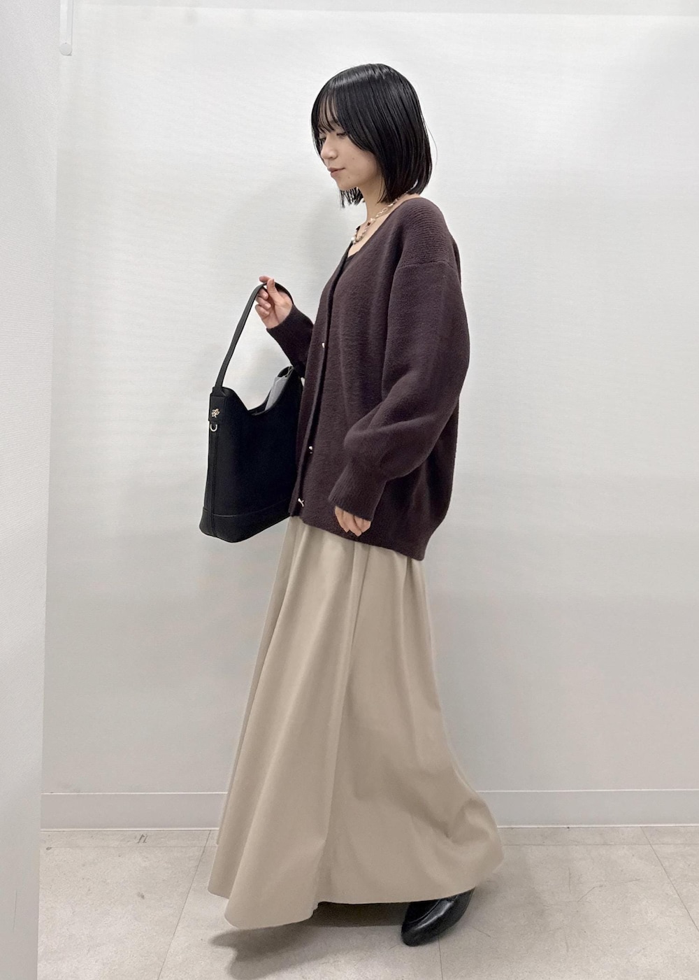 ベージュ系のスカート、ブラウン系のカーディガン/ボレロ、ブラック系のローファーを着用したレディースの秋コーディネートの3枚目の写真