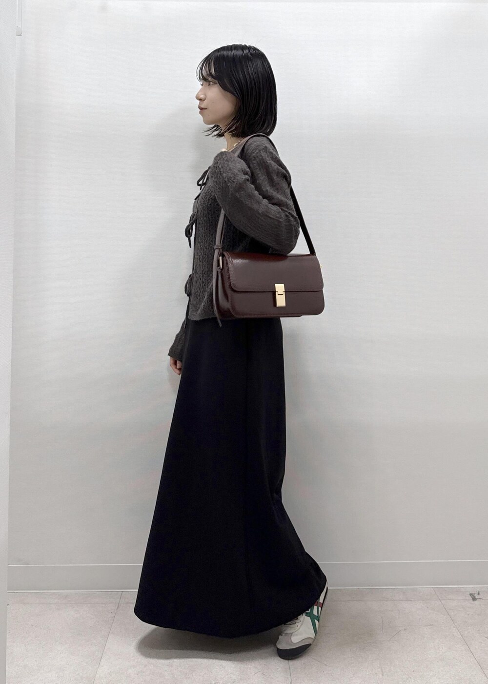 ブラック系のスカート、ブラウン系のカーディガン/ボレロ、レッド系のショルダーバッグを着用したレディースの秋コーディネートの4枚目の写真