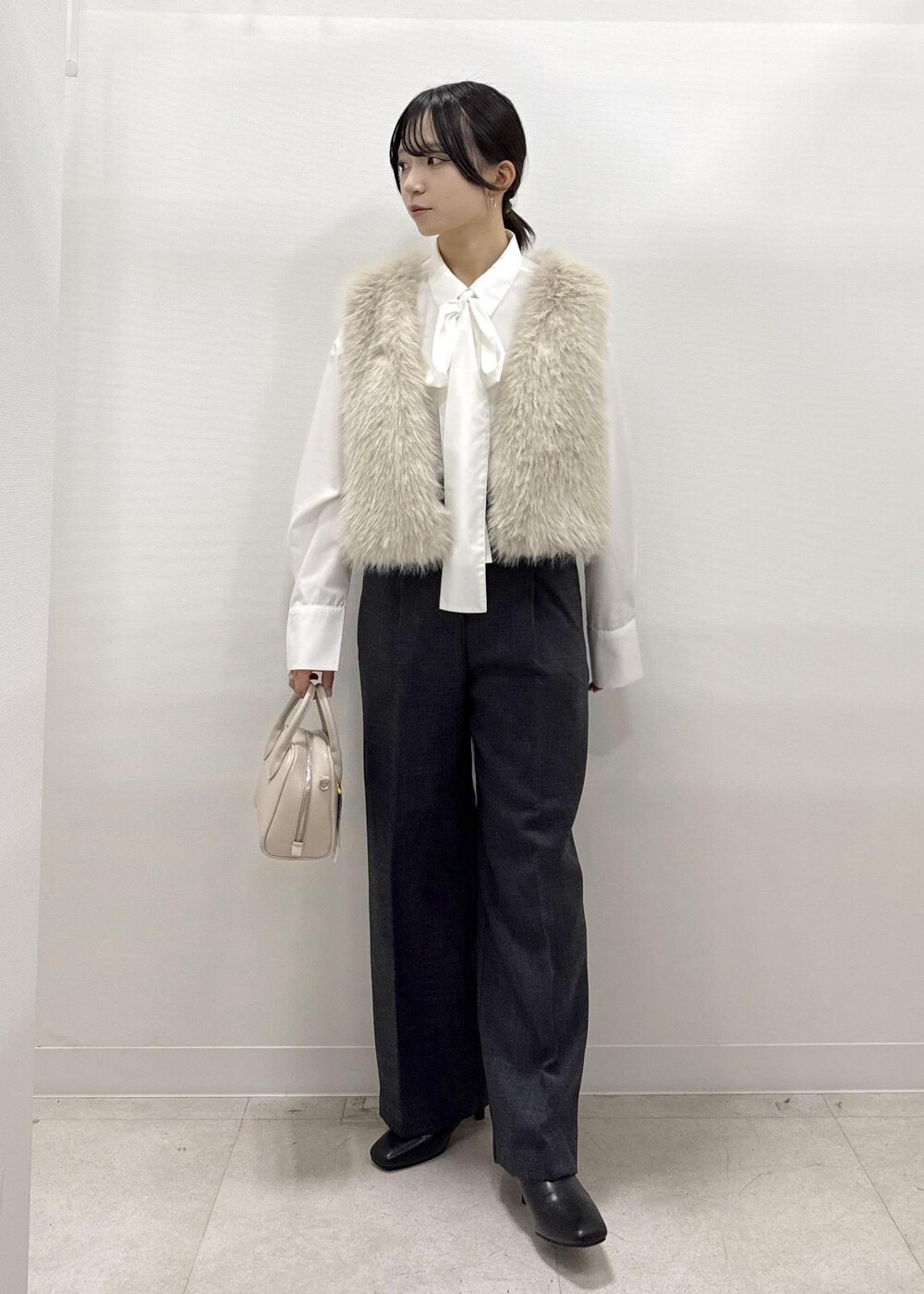 ベージュ系のベスト、ホワイト系のシャツ/ブラウス、グレー系のスラックスを着用したレディースの秋コーディネートの8枚目の写真