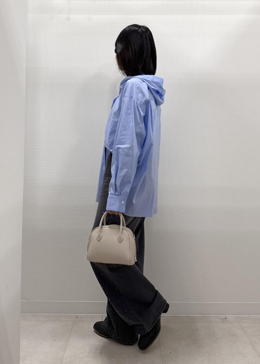 ブラック系のデニムパンツ、ブラック系のブーツ、ベージュ系のショルダーバッグを着用したレディースの秋コーディネートの3枚目の写真