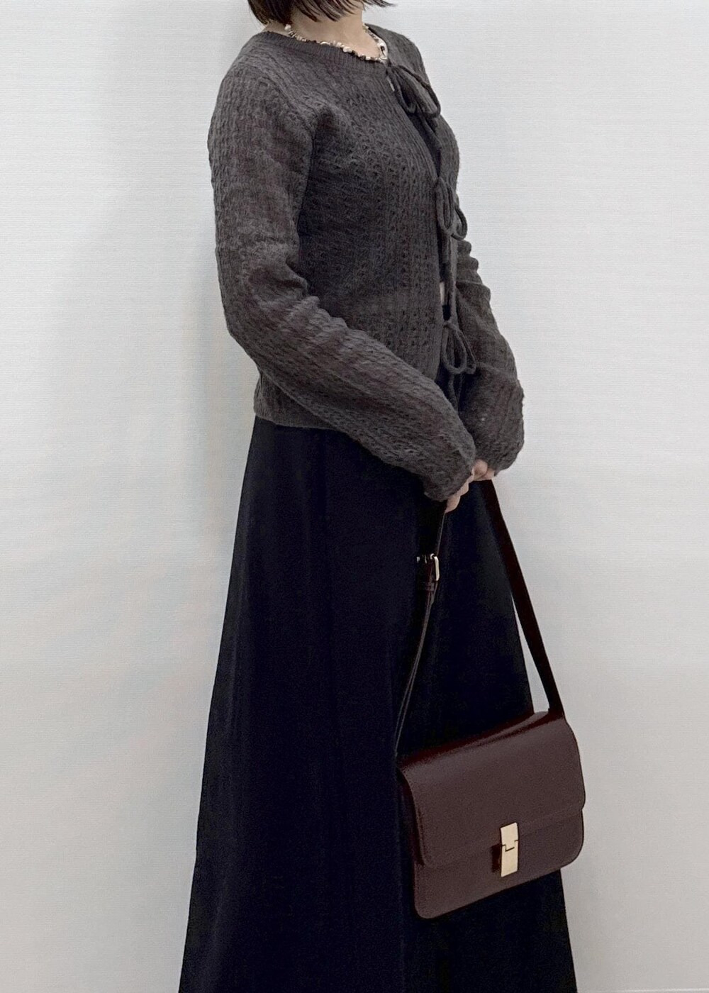 ブラック系のスカート、ブラウン系のカーディガン/ボレロ、レッド系のショルダーバッグを着用したレディースの秋コーディネートの9枚目の写真