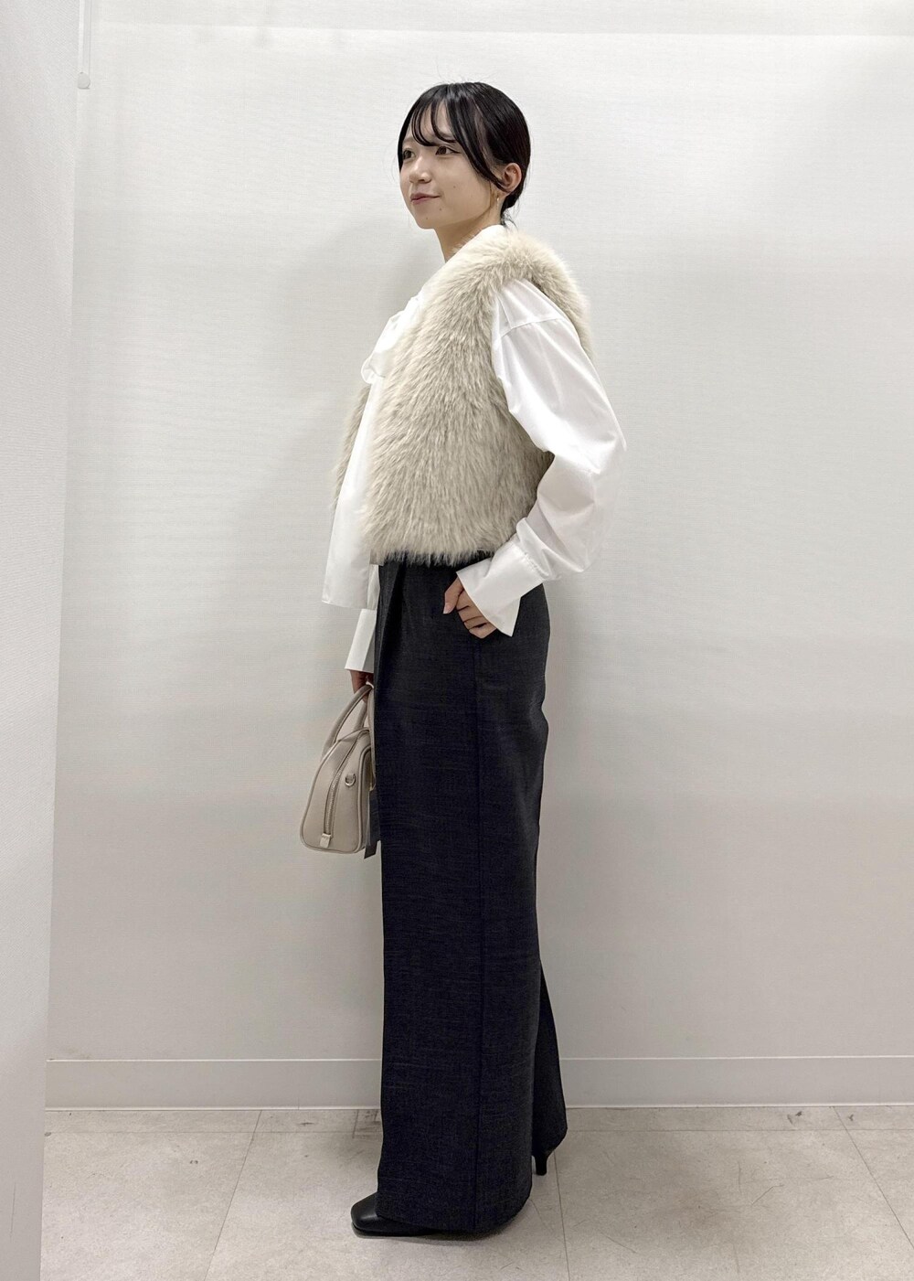 ベージュ系のベスト、ホワイト系のシャツ/ブラウス、グレー系のスラックスを着用したレディースの秋コーディネートの4枚目の写真