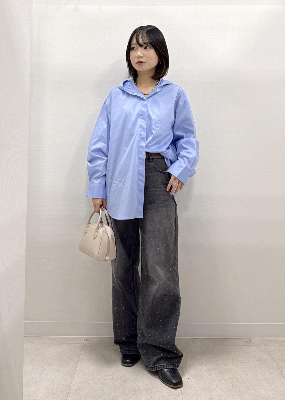 ブラック系のデニムパンツ、ブラック系のブーツ、ベージュ系のショルダーバッグを着用したレディースの秋コーディネートの7枚目の写真