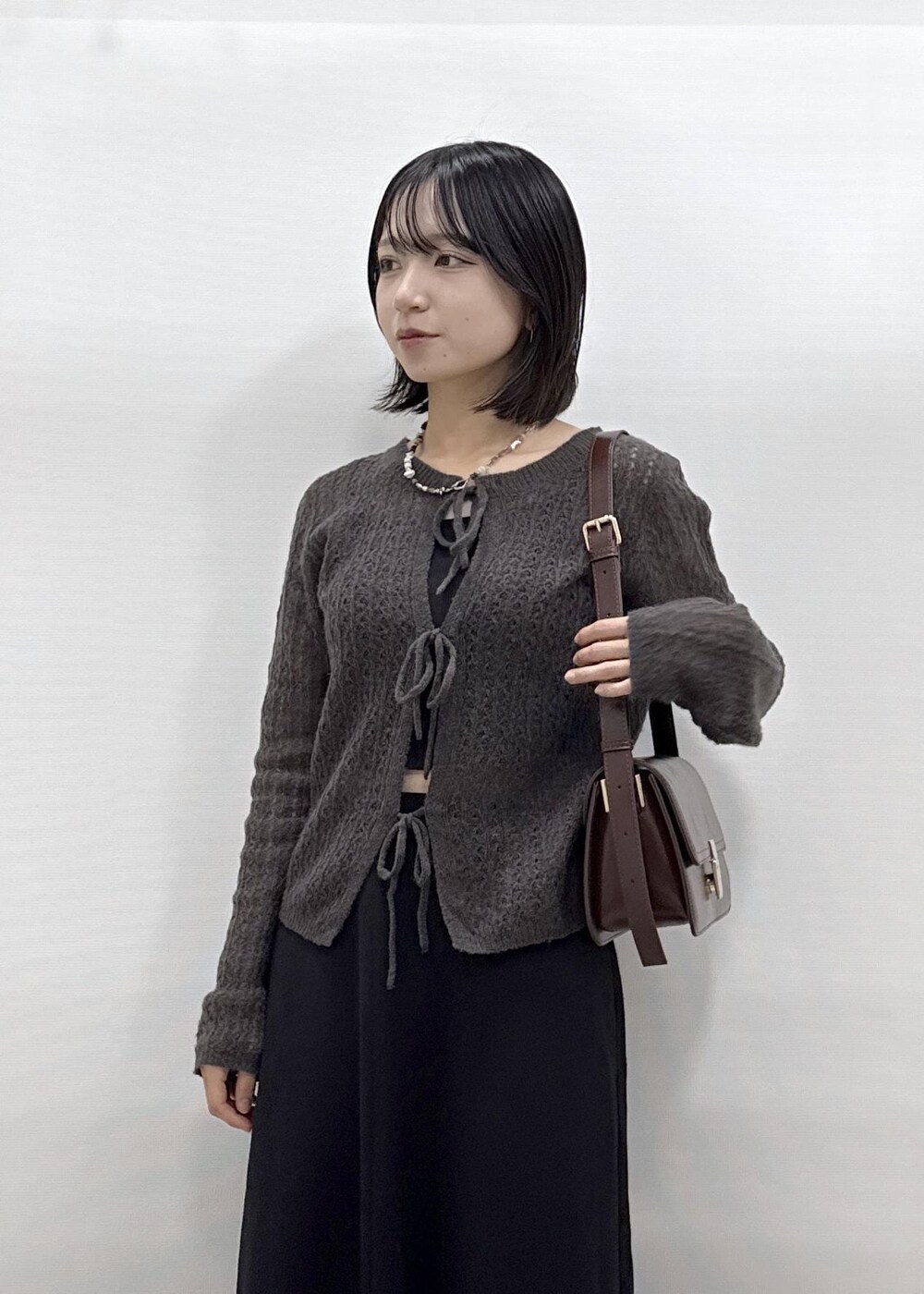 ブラック系のスカート、ブラウン系のカーディガン/ボレロ、レッド系のショルダーバッグを着用したレディースの秋コーディネートの7枚目の写真