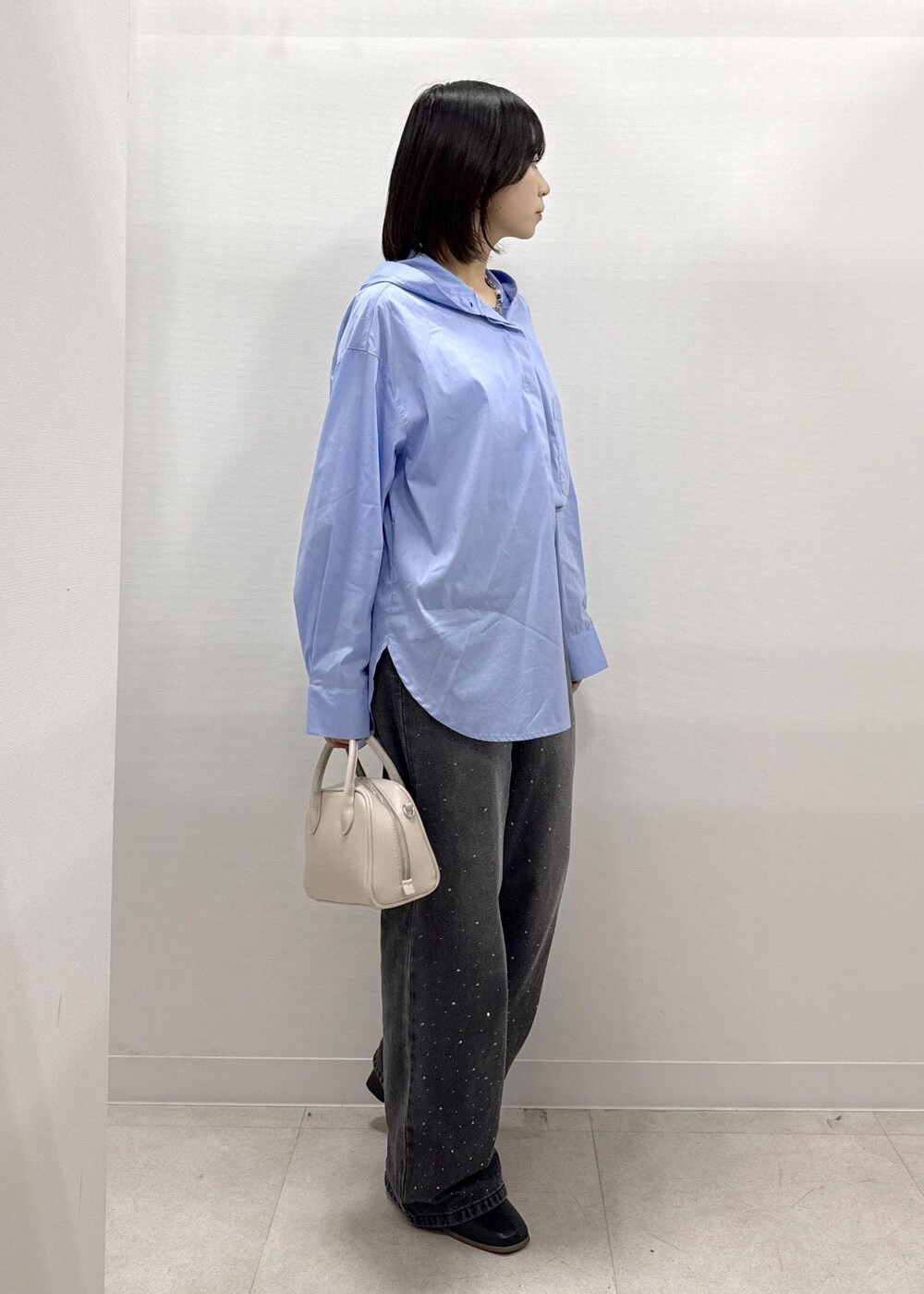 ブラック系のデニムパンツ、ブラック系のブーツ、ベージュ系のショルダーバッグを着用したレディースの秋コーディネートの10枚目の写真