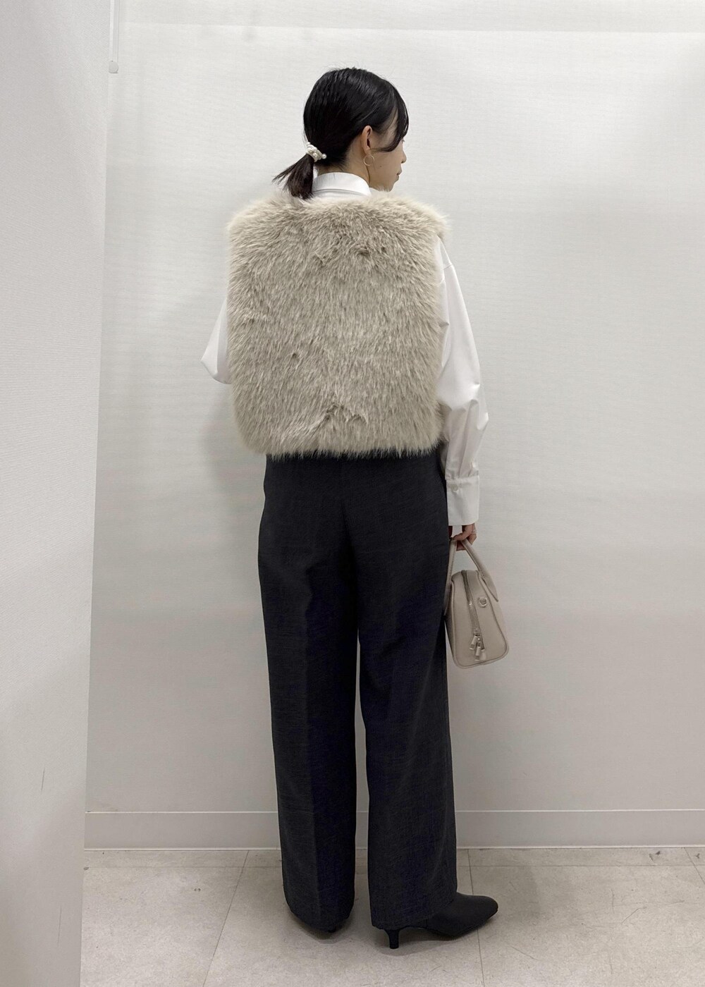 ベージュ系のベスト、ホワイト系のシャツ/ブラウス、グレー系のスラックスを着用したレディースの秋コーディネートの6枚目の写真