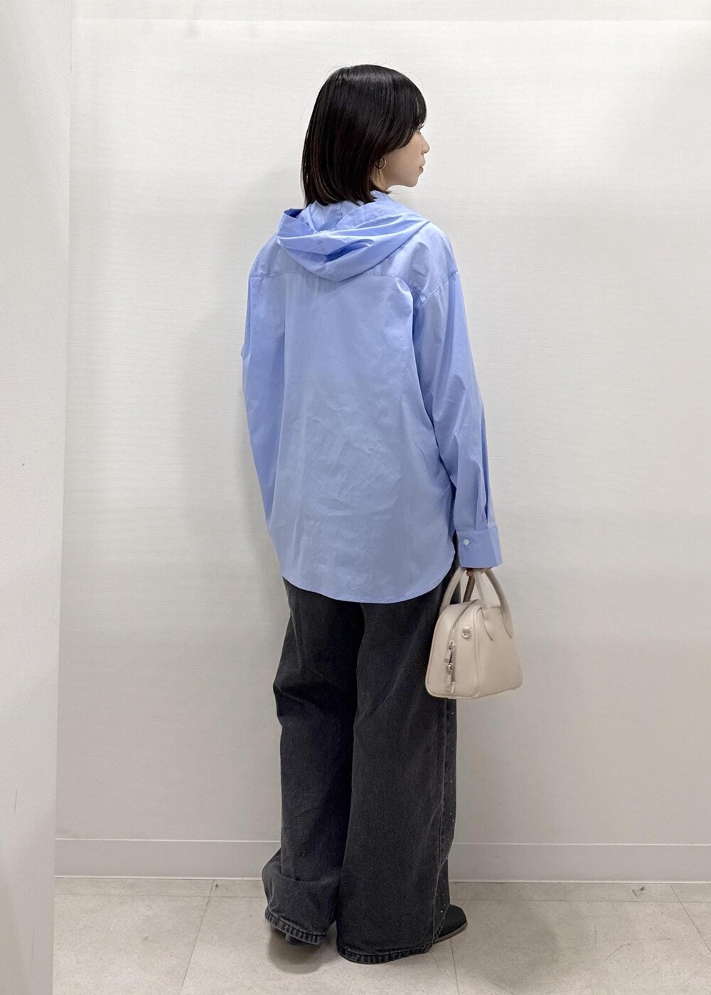 ブラック系のデニムパンツ、ブラック系のブーツ、ベージュ系のショルダーバッグを着用したレディースの秋コーディネートの6枚目の写真