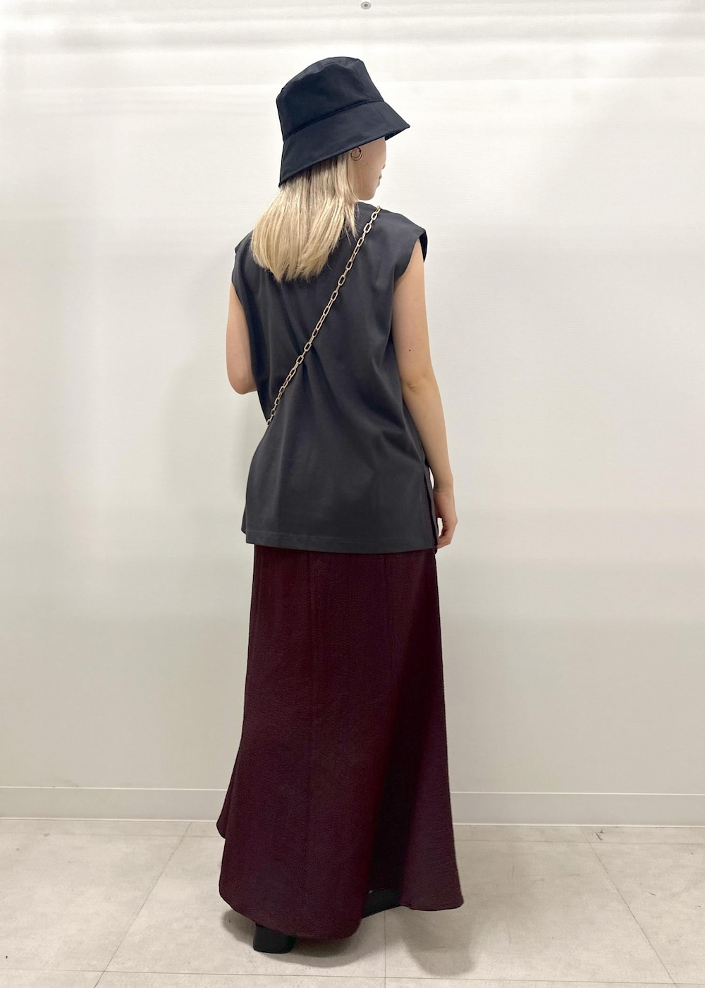 ブラック系のショルダーバッグ、ゴールド系のサンダル、グレー系のTシャツ/カットソーを着用したレディースの夏コーディネートの6枚目の写真