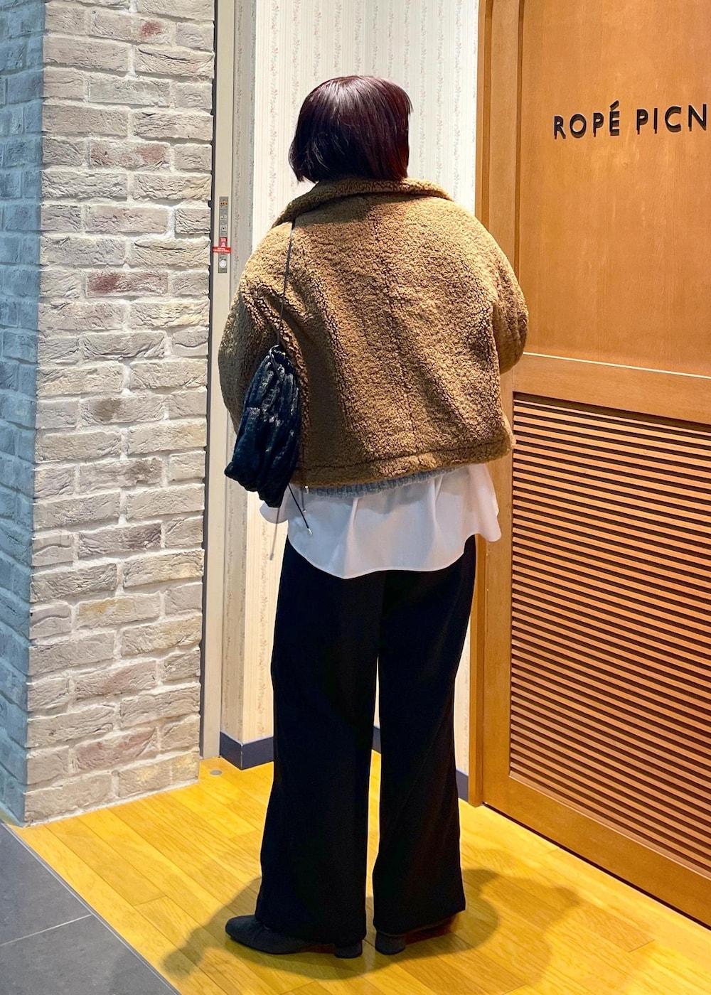 イエロー系のムートンコート、ブラック系のその他パンツ、グレー系のパンプスを着用したレディースの冬コーディネートの3枚目の写真