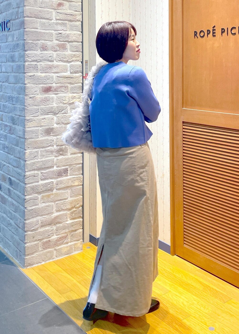 ブルー系のカーディガン/ボレロ、ベージュ系のスカート、ブルー系のTシャツ/カットソーを着用したレディースの冬コーディネートの4枚目の写真