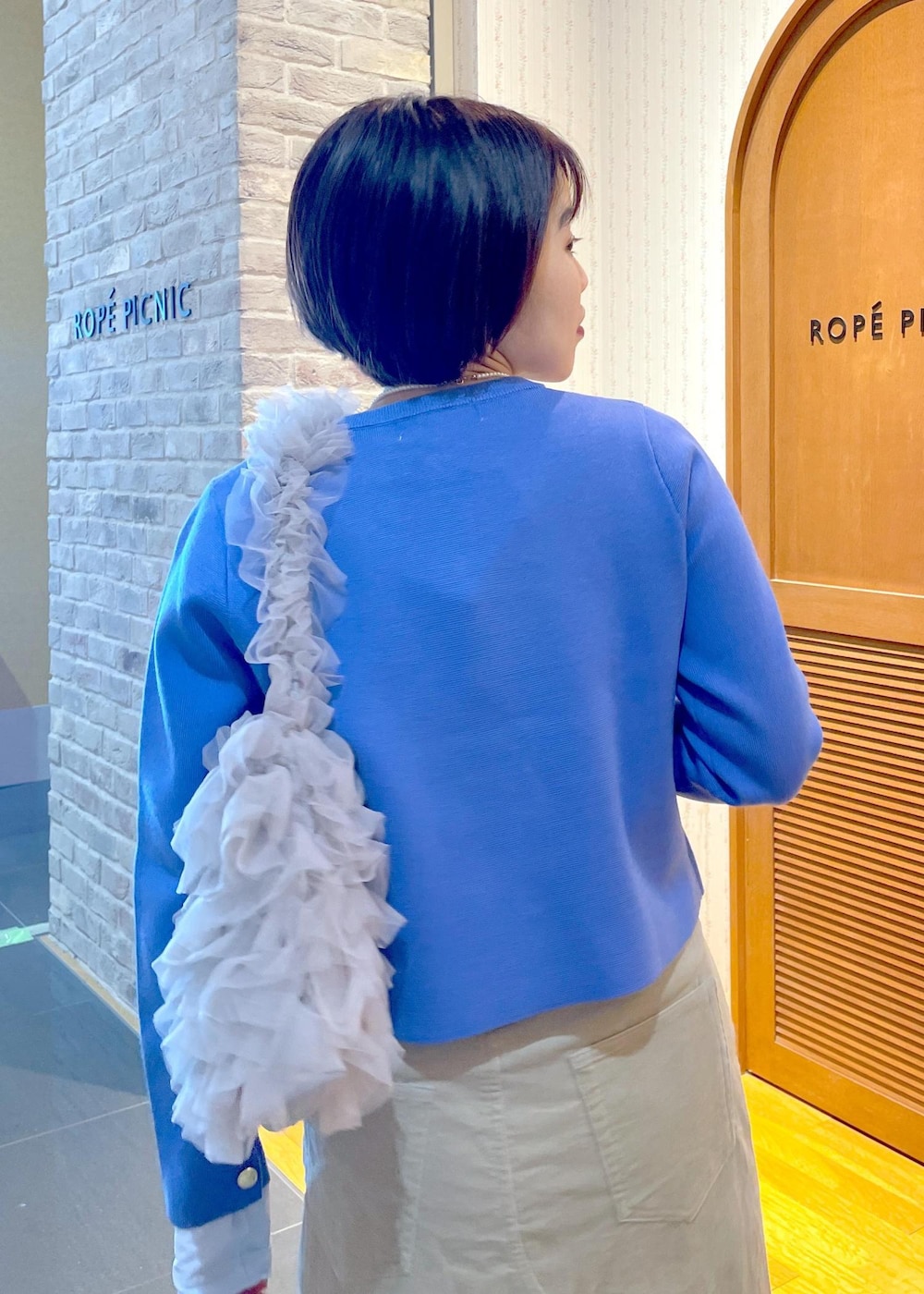 ブルー系のカーディガン/ボレロ、ベージュ系のスカート、ブルー系のTシャツ/カットソーを着用したレディースの冬コーディネートの7枚目の写真