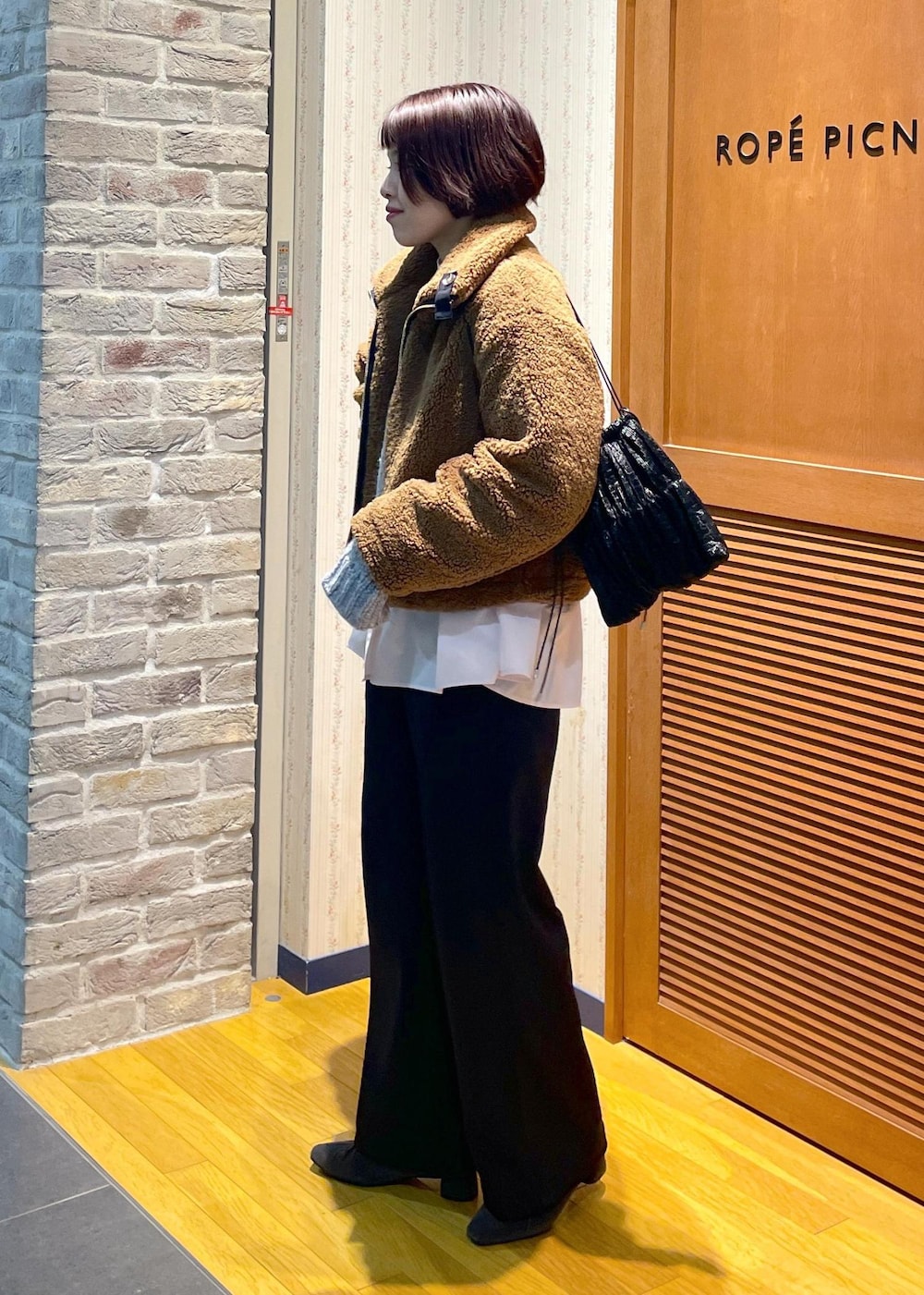 イエロー系のムートンコート、ブラック系のその他パンツ、グレー系のパンプスを着用したレディースの冬コーディネートの2枚目の写真