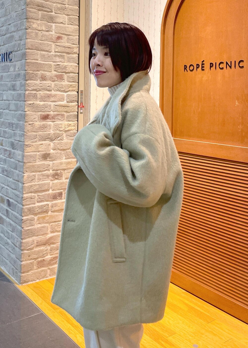 ホワイト系のニット/セーター、グリーン系のその他アウター、ブラック系のショルダーバッグを着用したレディースの冬コーディネートの7枚目の写真